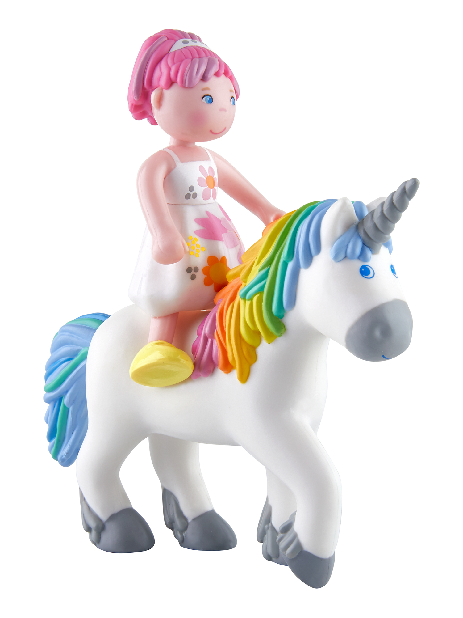 Ein Spielzeugmädchen reitet auf einem weißen Einhorn mit Regenbogenmähne und -schwanz. Mädchen trägt ein weißes Kleid mit Blumen.
