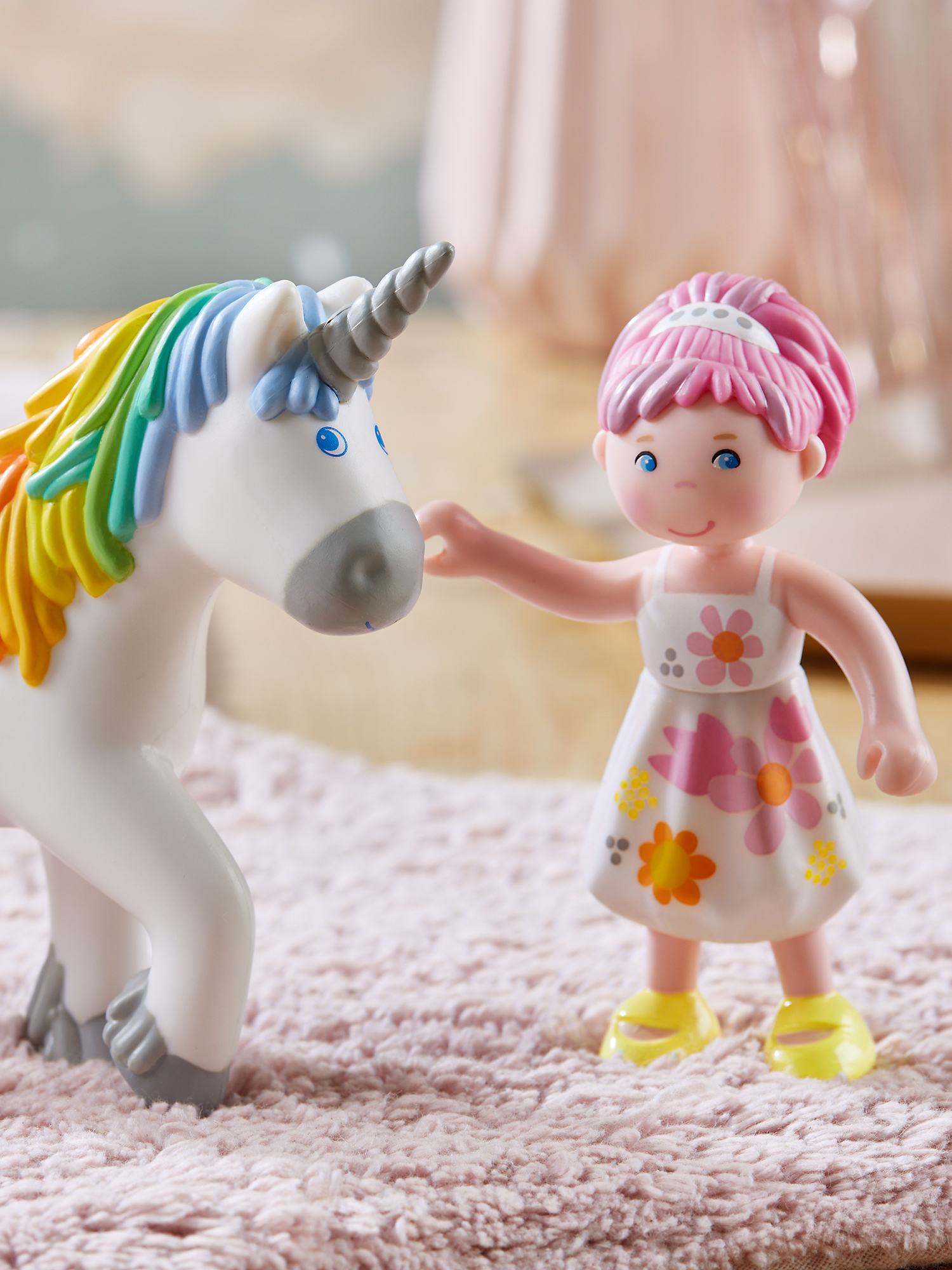 Ein Mädchen und ein Einhorn-Spielzeug. Das Mädchen in weißem Kleid mit Blumen, Einhorn mit Regenbogenmähne.