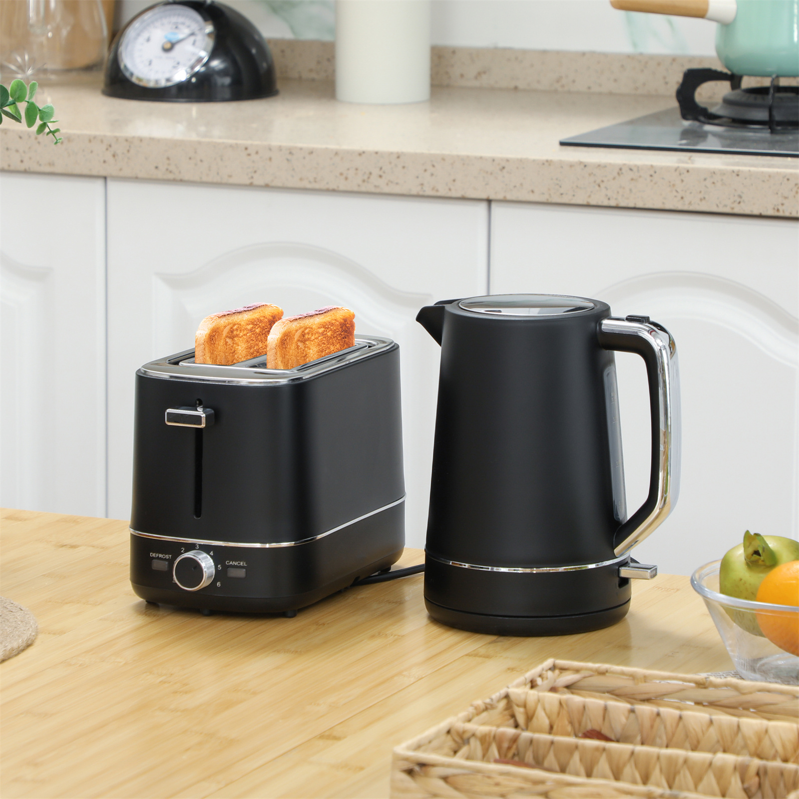 Ein schwarzer Toaster und Wasserkocher auf einem Holztisch. Zwei geröstete Brotscheiben im Toaster.