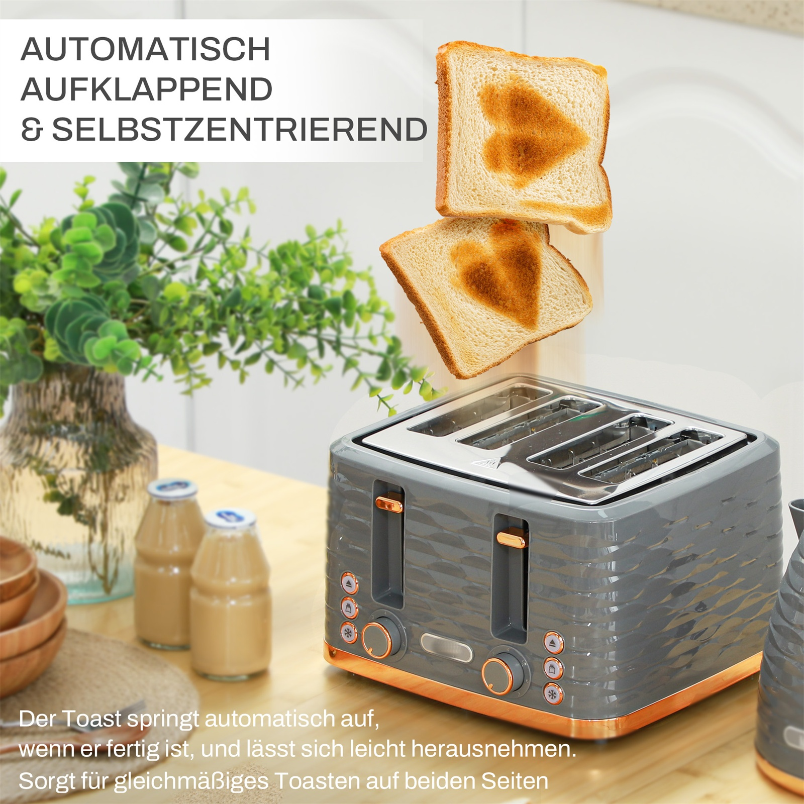 Grauer Toaster mit zwei Toastscheiben mit herzförmigen Aussparungen, und eine Pflanze.