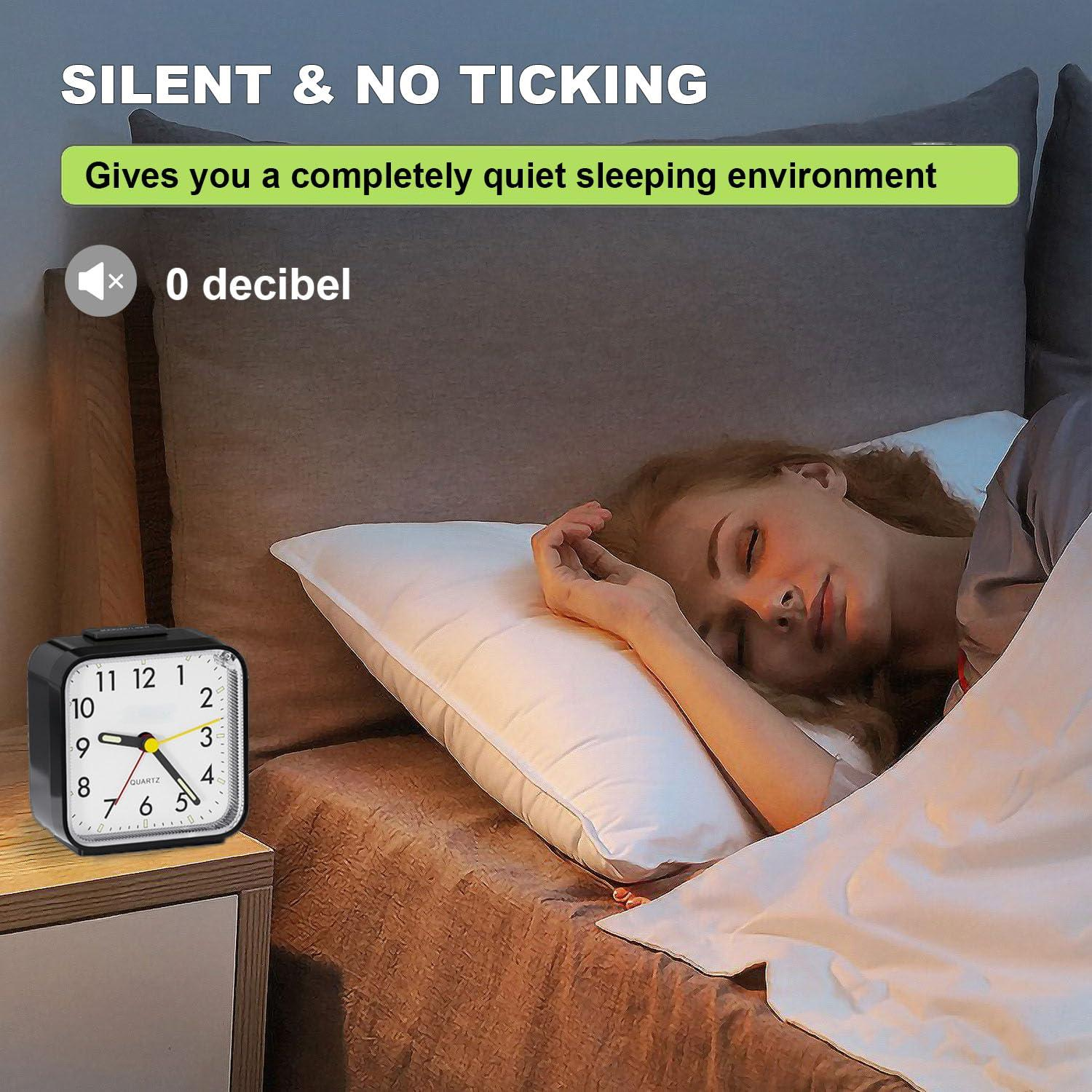 Ein schwarzer Wecker auf einem Nachttisch. Eine Frau schläft im Bett. Text: Silent & No Ticking.
