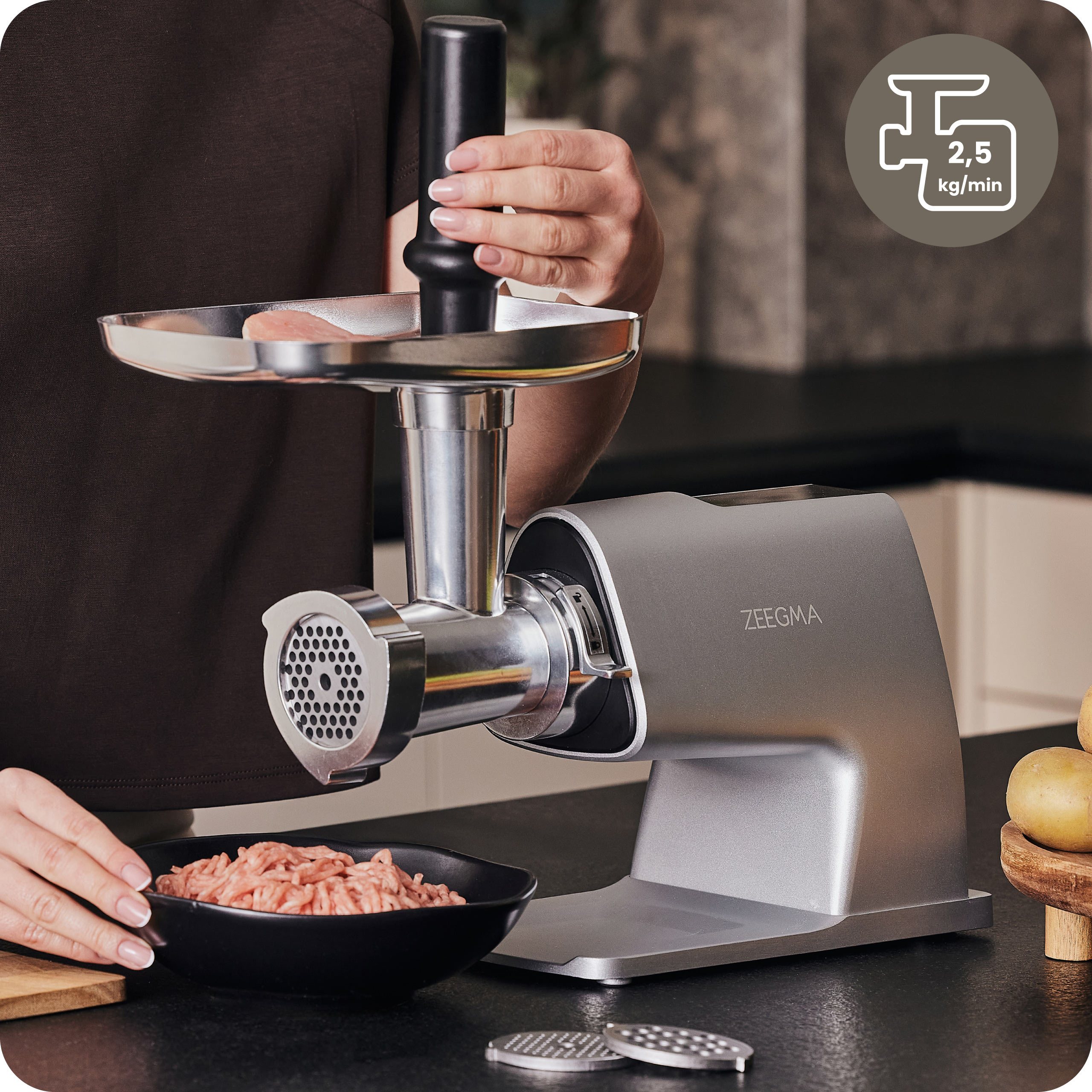 Kobieta mieląca mięso w srebrnej maszynce do mięsa. Widoczna miska z mięsem mielonym i ostrze.