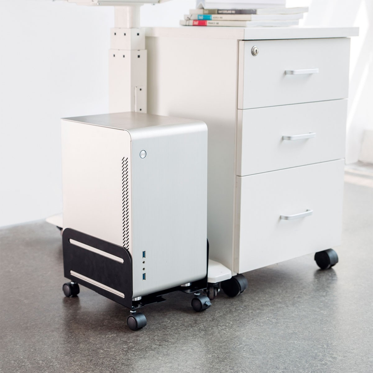 Un mobile bianco con una torre del computer su un carrello, accanto a un archivio bianco.