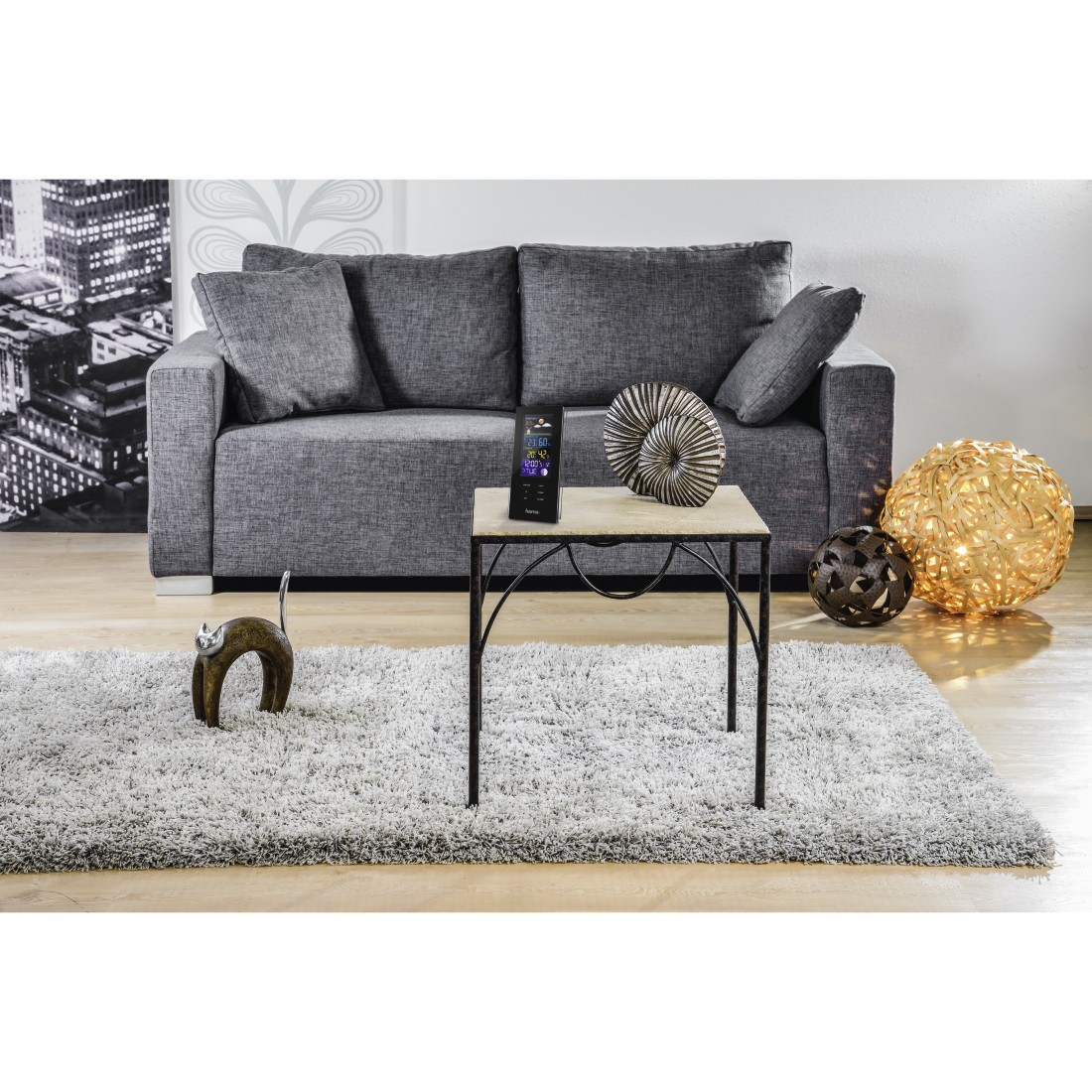 Wohnzimmer mit grauem Sofa, Teppich, Couchtisch mit Dekor und Stadtbildmalerei an der Wand.