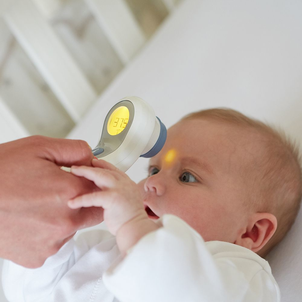 Dziecko badane termometrem dousznym. Termometr jest skierowany na czoło dziecka.
