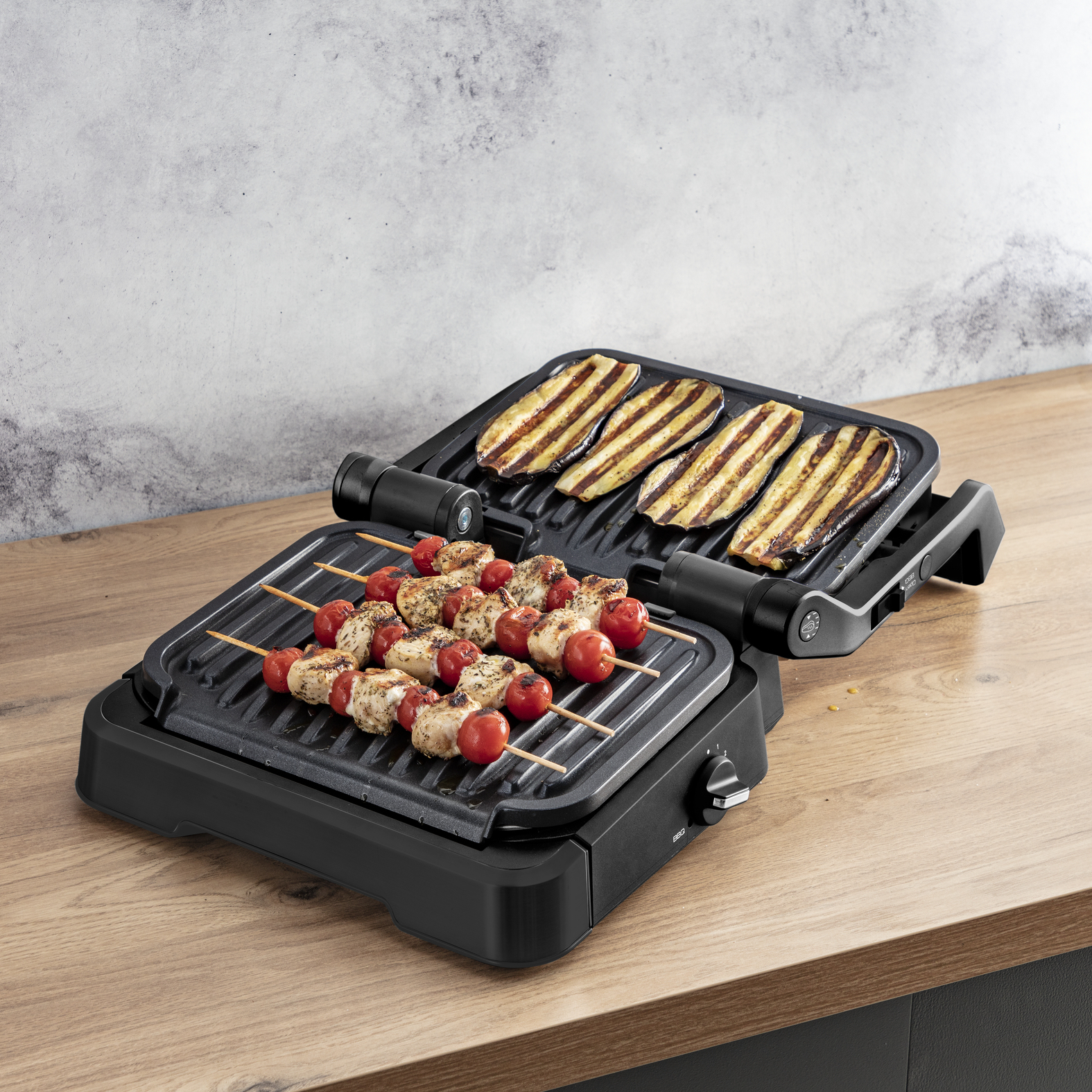 Grill z szaszłykami i grillowanym bakłażanem, na drewnianym stole.
