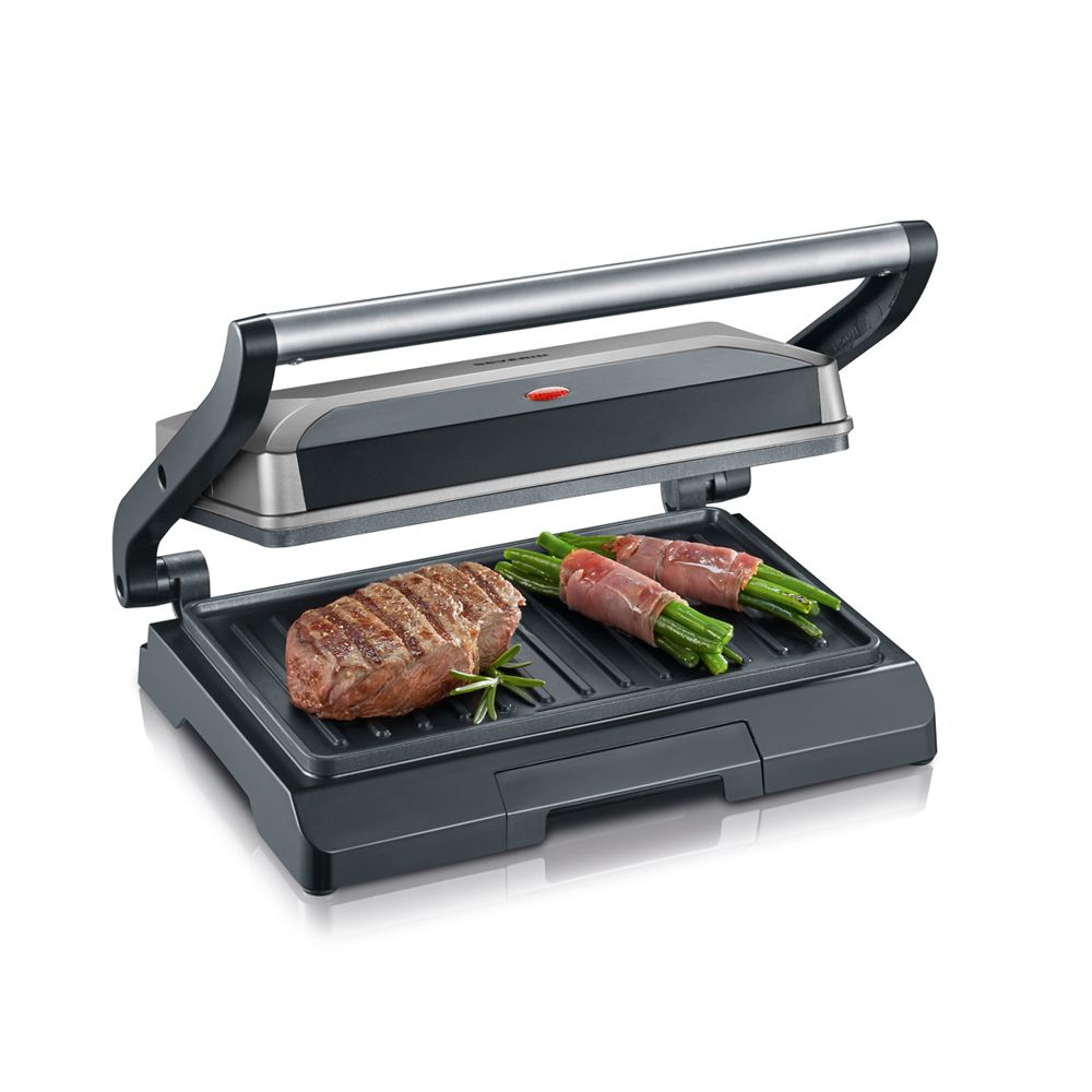 Een panini pers met een biefstuk en gewikkelde asperges op het kookoppervlak. Witte achtergrond.