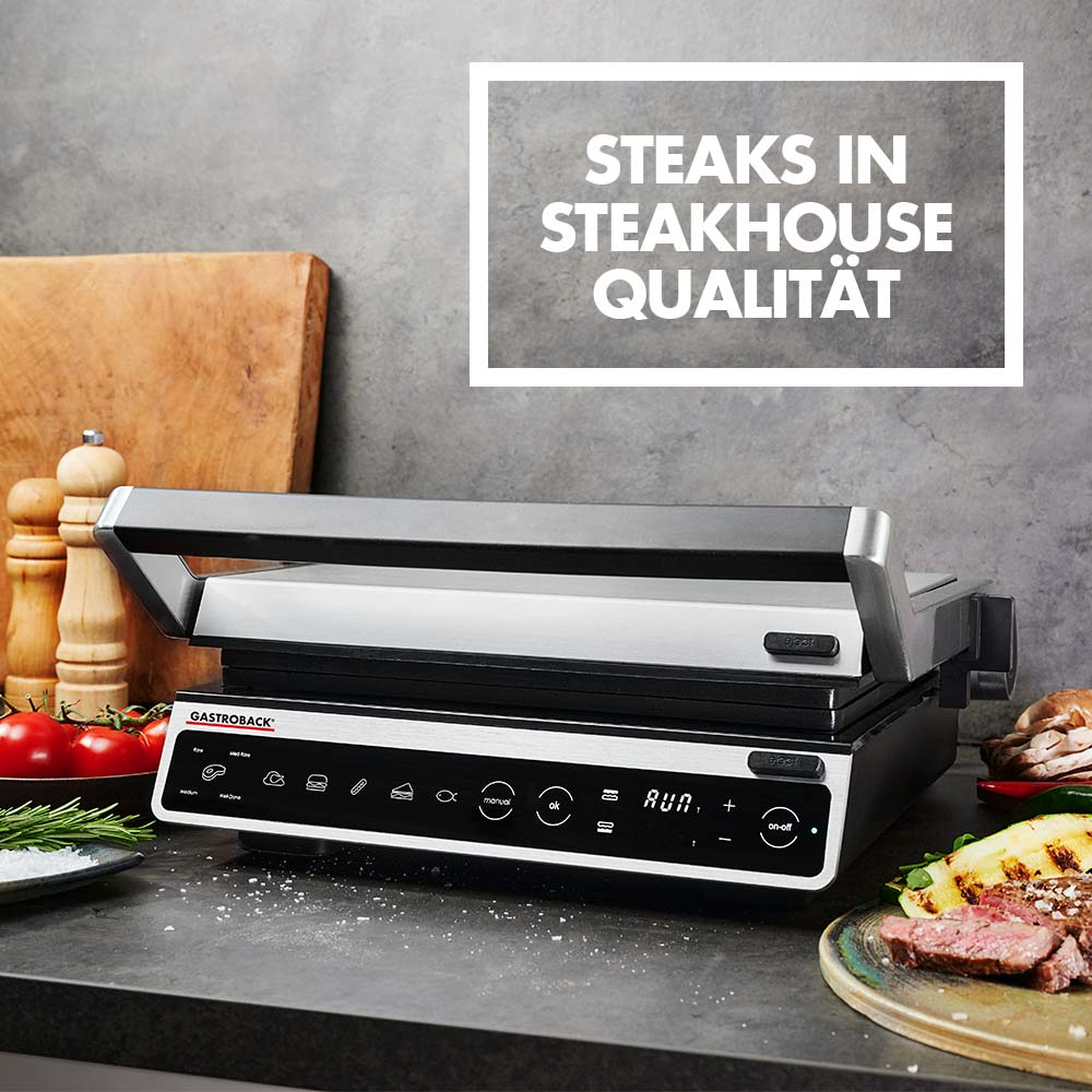 Gril avec nourriture, tomates et romarin. Texte : "Steaks in Steakhouse Qualität" dans une boîte grise.