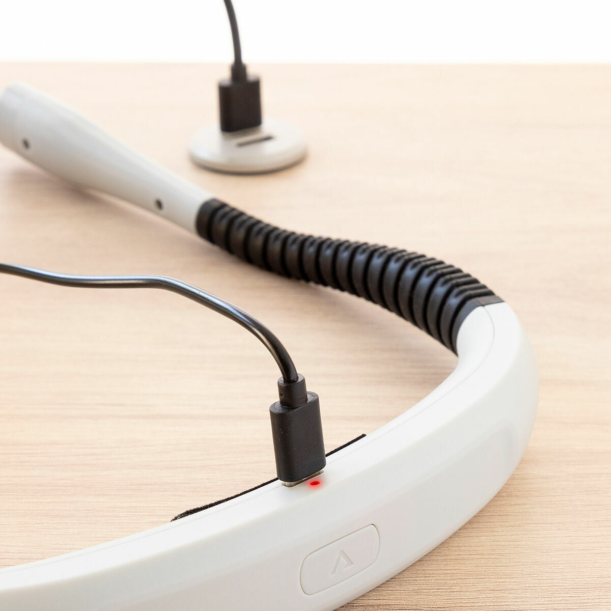Dispositivo di ricarica bianco e grigio con cavo USB-C nero collegato. Una luce rossa è accesa.