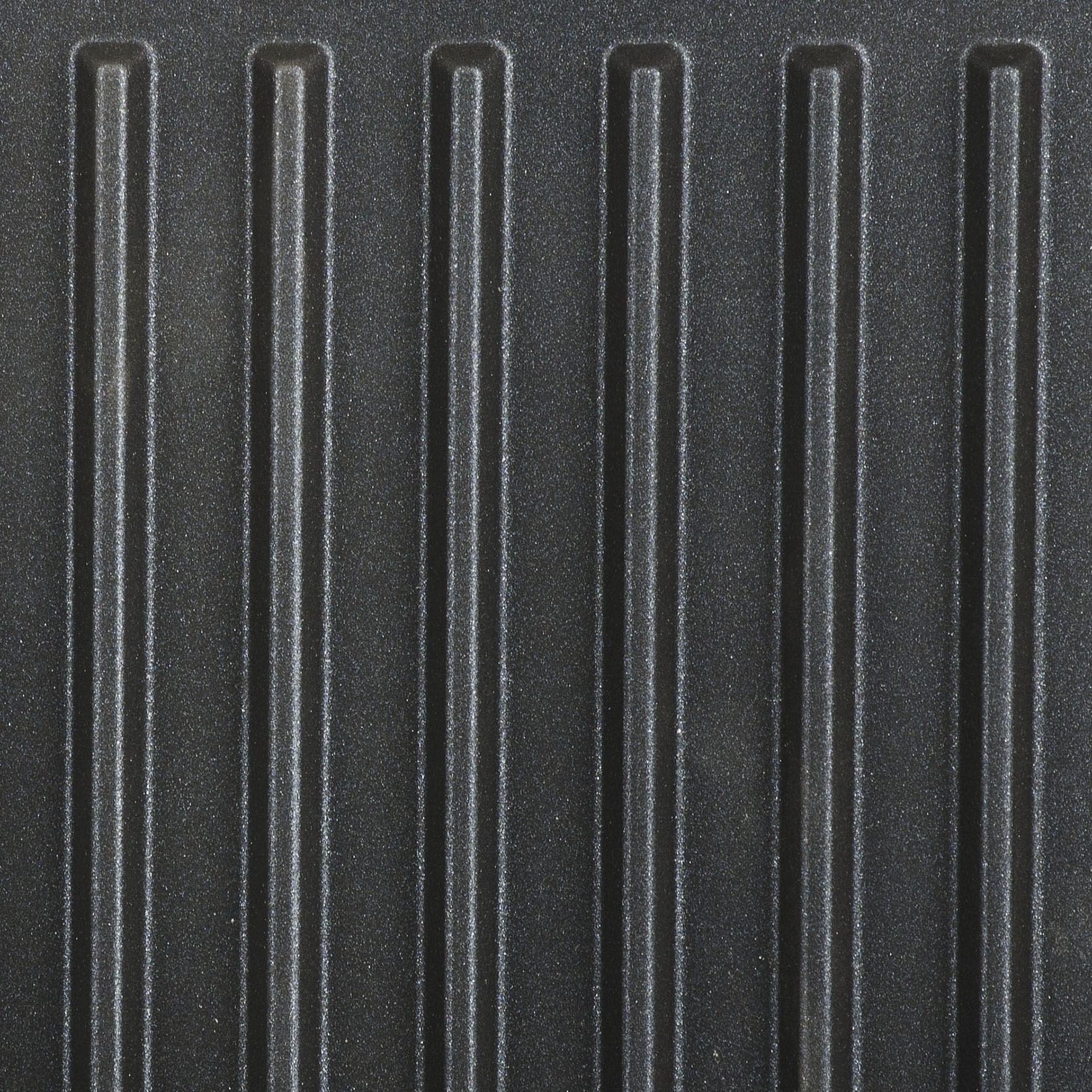 Nahaufnahme einer schwarzen Grillfläche mit parallelen, vertikalen Rillen. Die Oberfläche hat eine Textur.