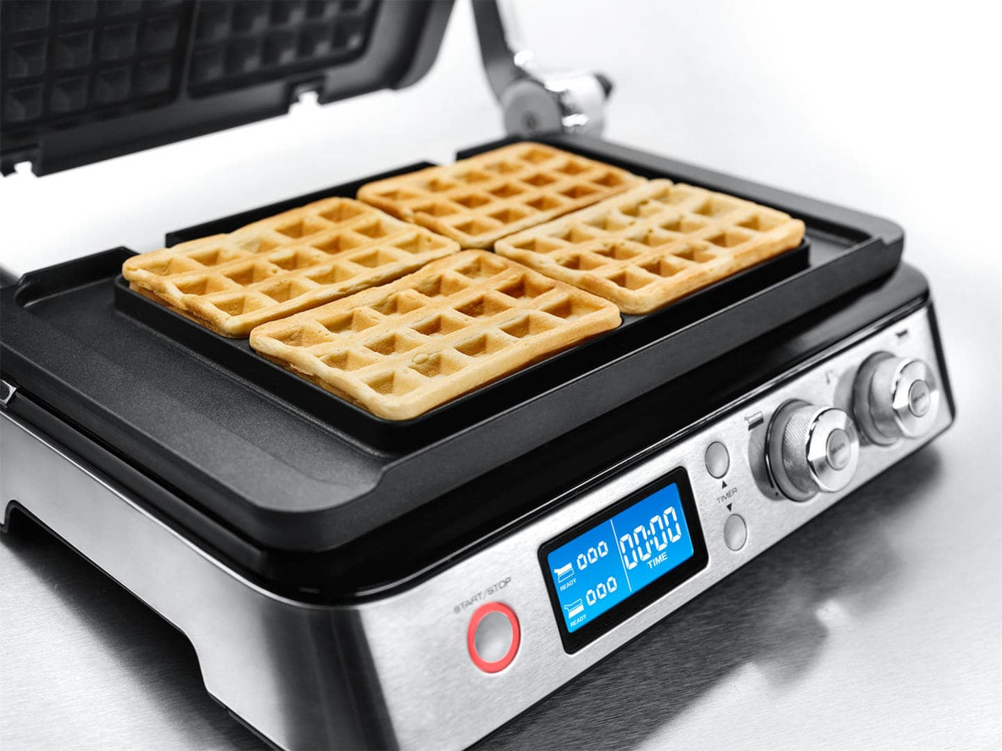 Ein Waffeleisen mit vier fertigen Waffeln. Das Gerät hat einen Timer und Knöpfe.