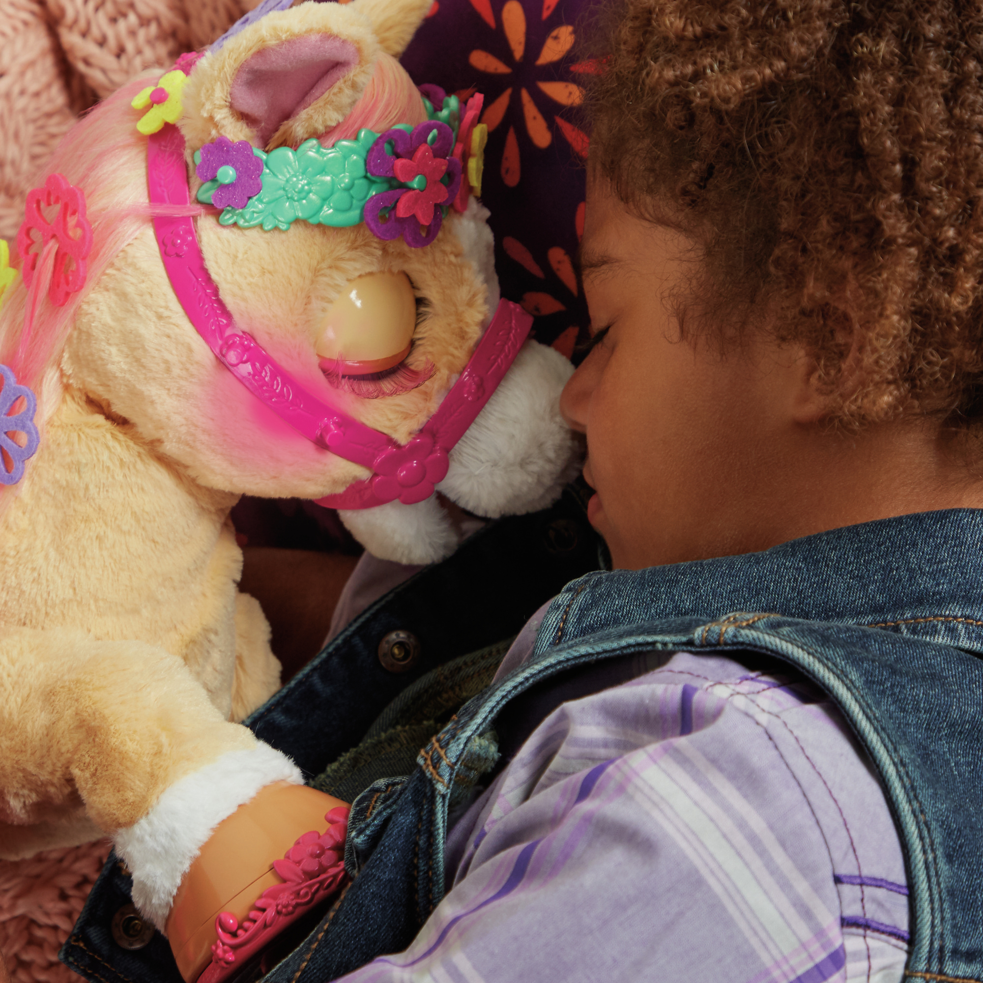 Ein Kind schläft neben einem Spielzeugpferd. Das Pony ist hellbraun mit rosa Haaren und Zaumzeug.
