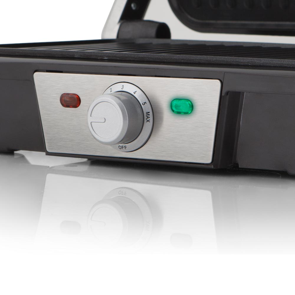 Primer plano de una parrilla con panel de control. Tiene un dial y dos luces en un panel plateado.