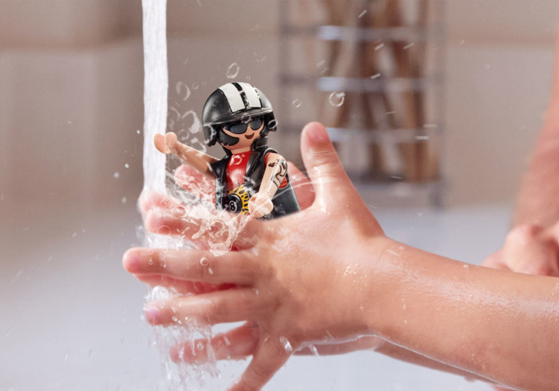 Dziecięce dłonie pod wodą z zabawką motocyklistą. Rozbryzgi wody i jasne tło.