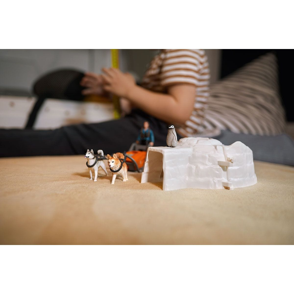 Scène de jouet avec des chiens, une charrette, un pingouin et un igloo.
