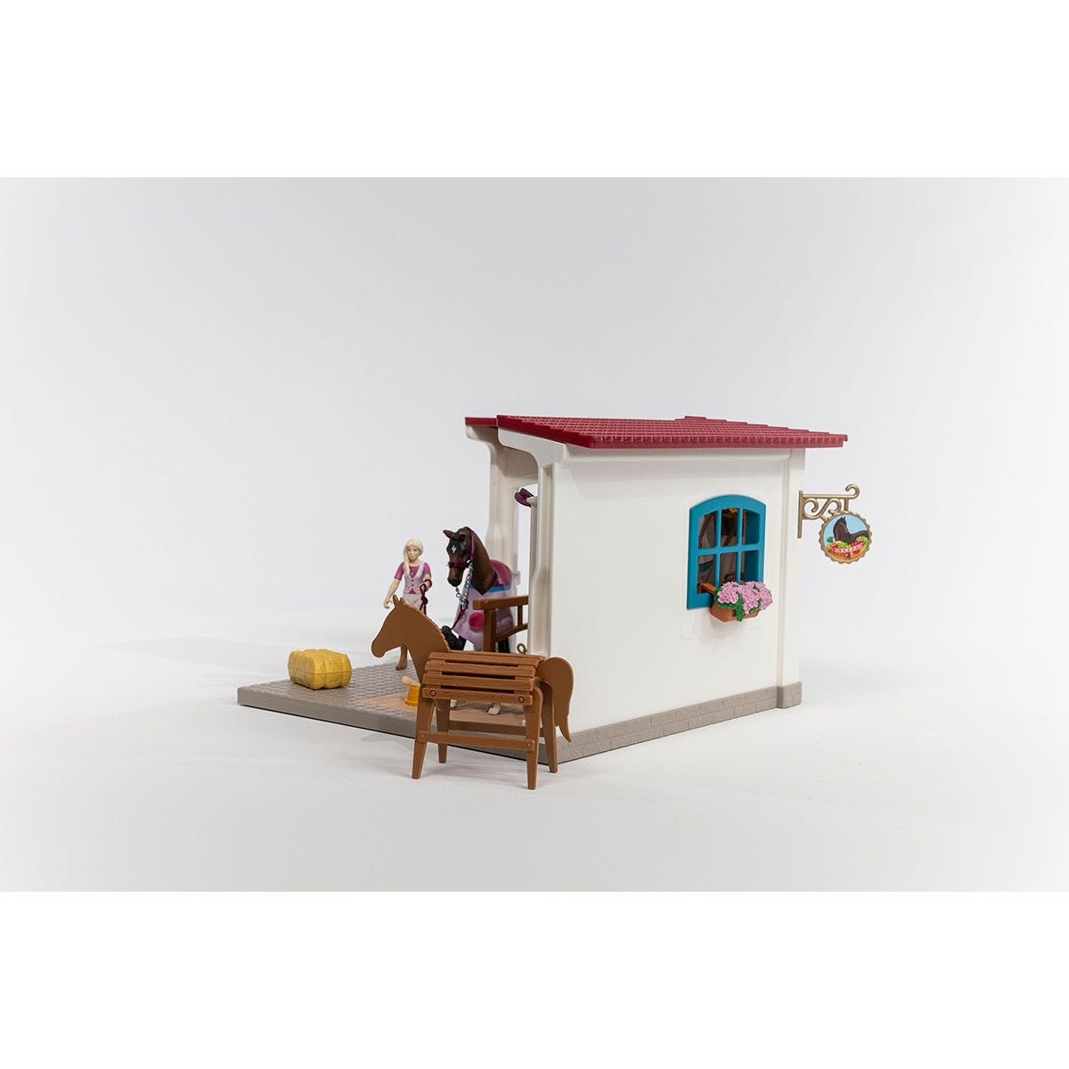 Spielzeugstall mit Pferd und Figur. Die Figur ist im Stall. Ein Pferd ist außerhalb des Stalls.
