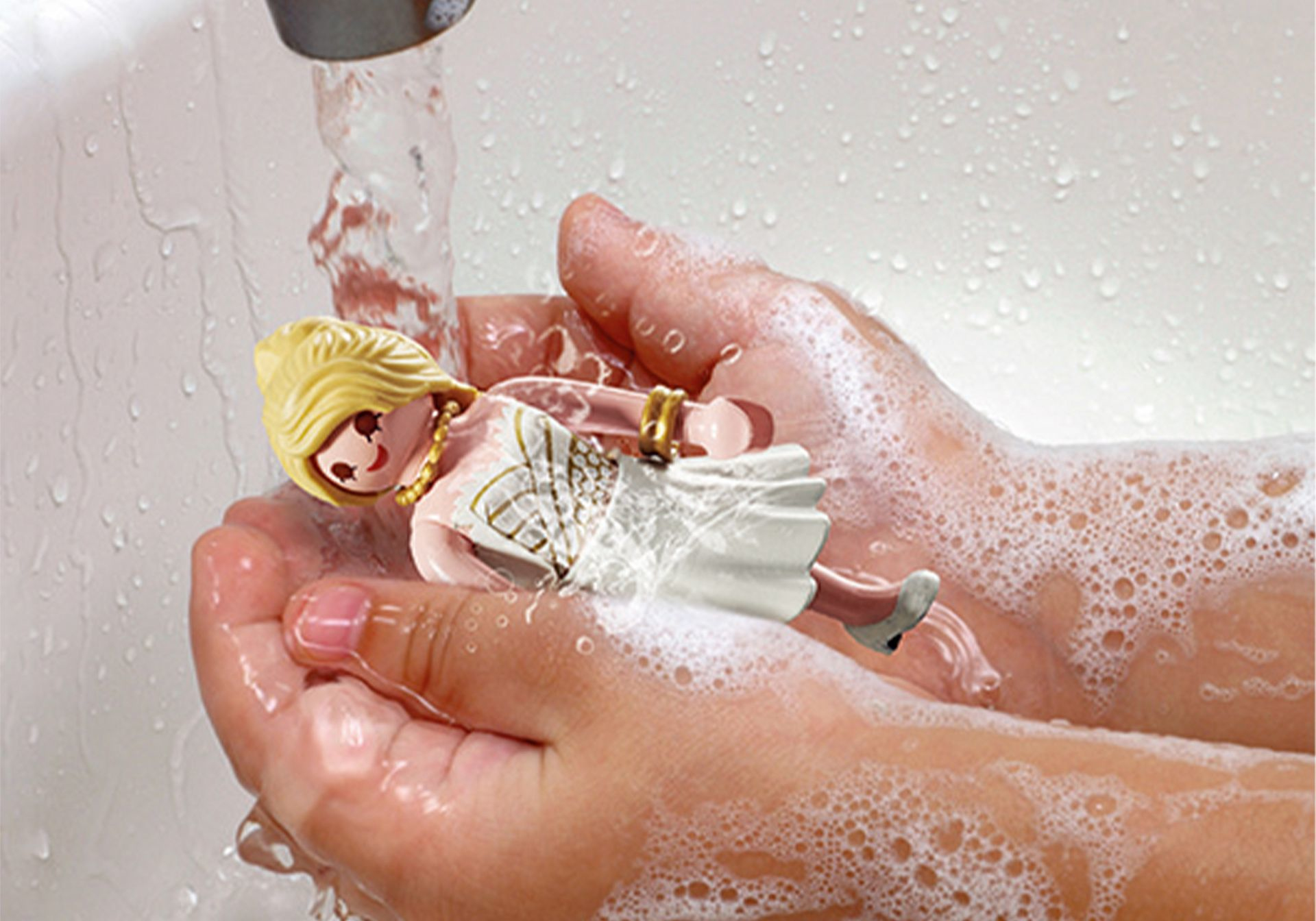 Ręce myjące lalkę w mydlanej wodzie pod kranem. Lalka jest blondynką, ubrana w białą sukienkę.