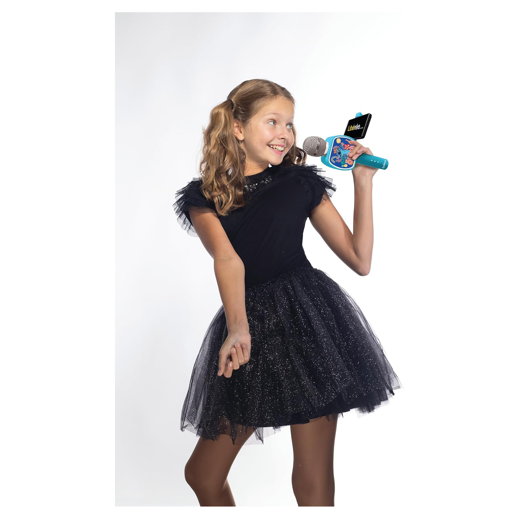 Dziewczyna trzymająca mikrofon, uśmiechnięta. Ma na sobie czarną sukienkę.