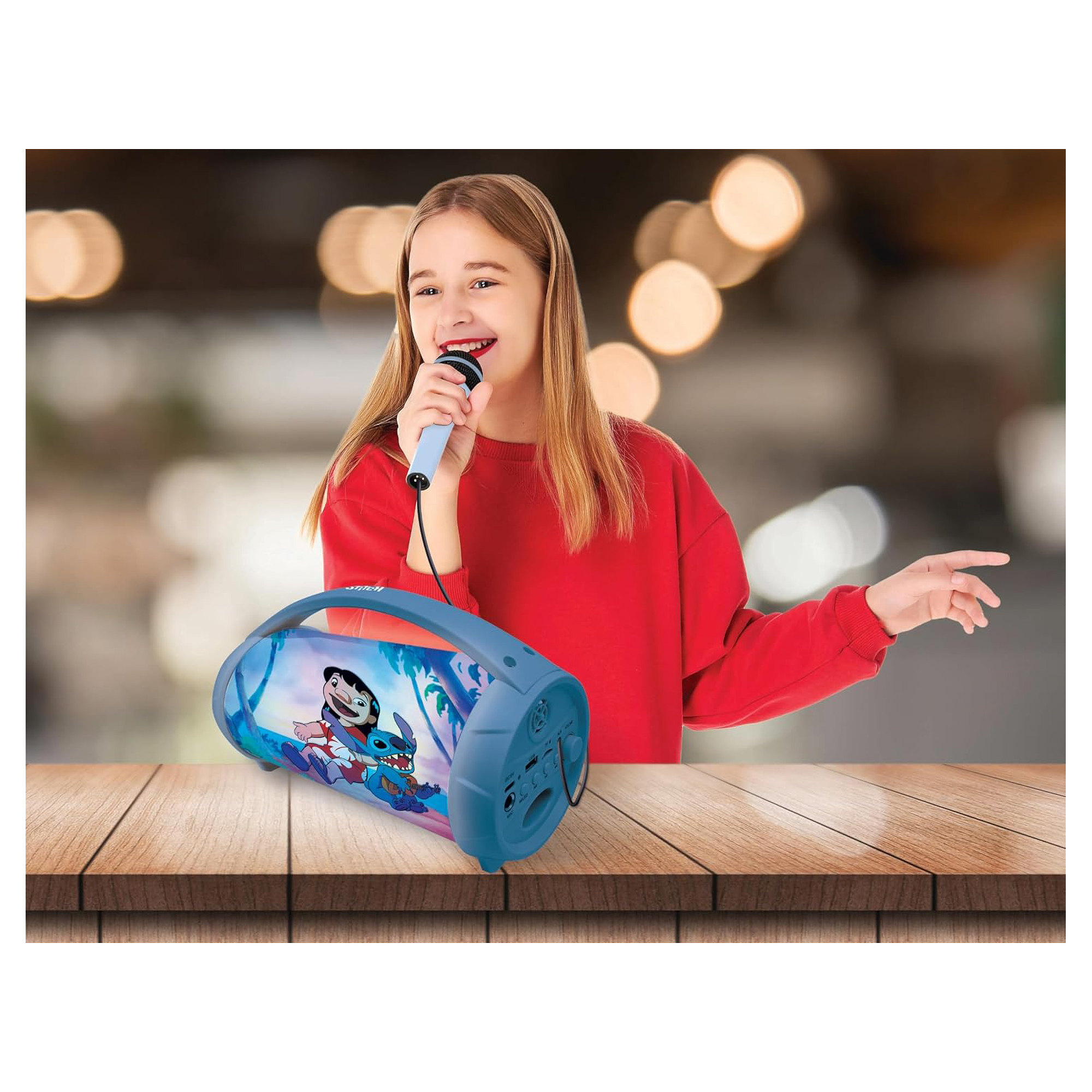 Una ragazza in rosso canta in un microfono, con un altoparlante blu Stitch accanto a lei su un tavolo di legno.