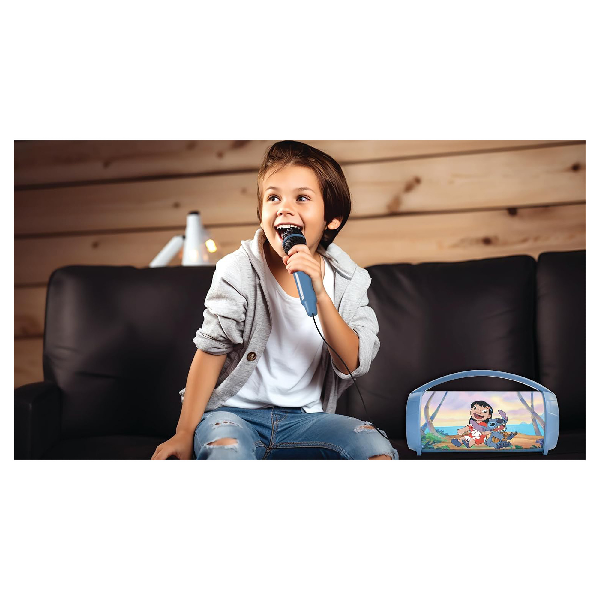 Un ragazzo canta in un microfono. Sorride, con un karaoke machine vicino.
