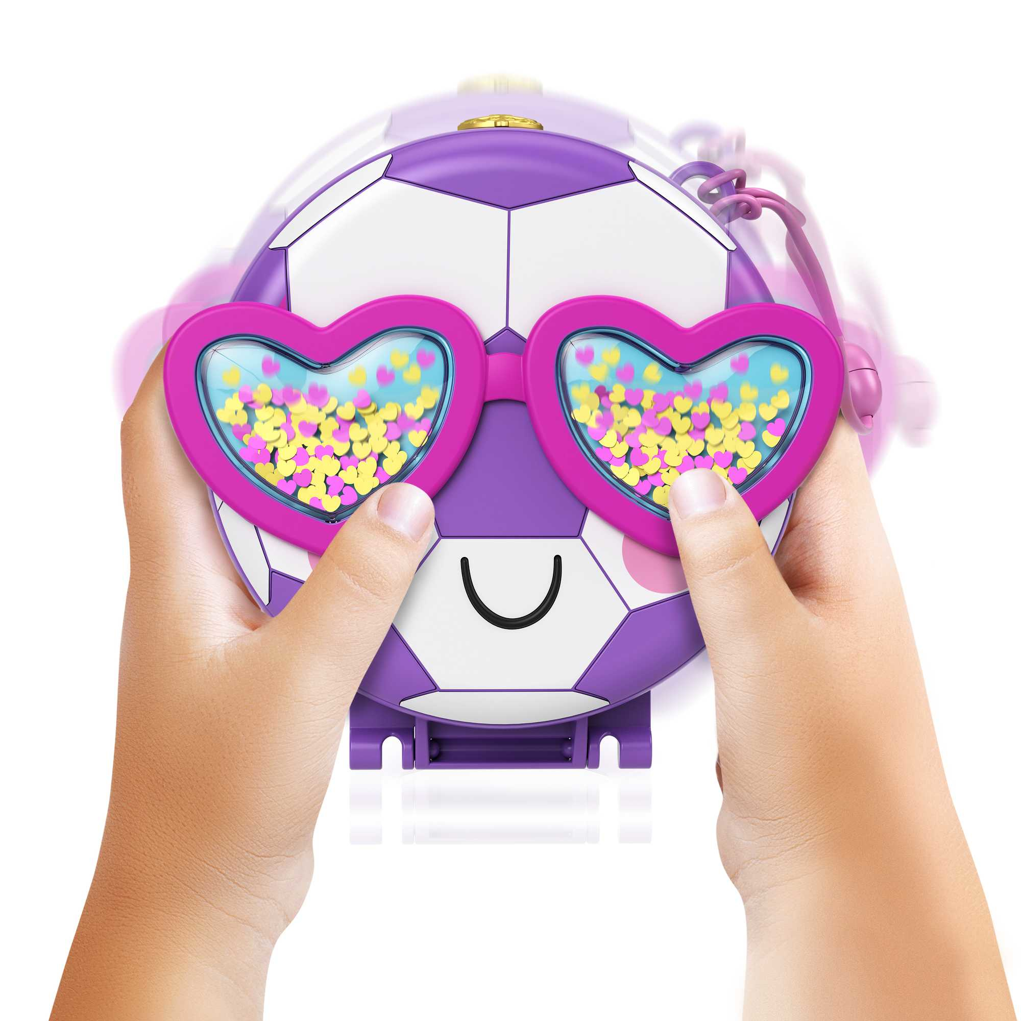 Hände halten ein fußballförmiges Spielzeug mit herzförmigen Brillen. Es ist lila und weiß. Die Herzen sind gelb.