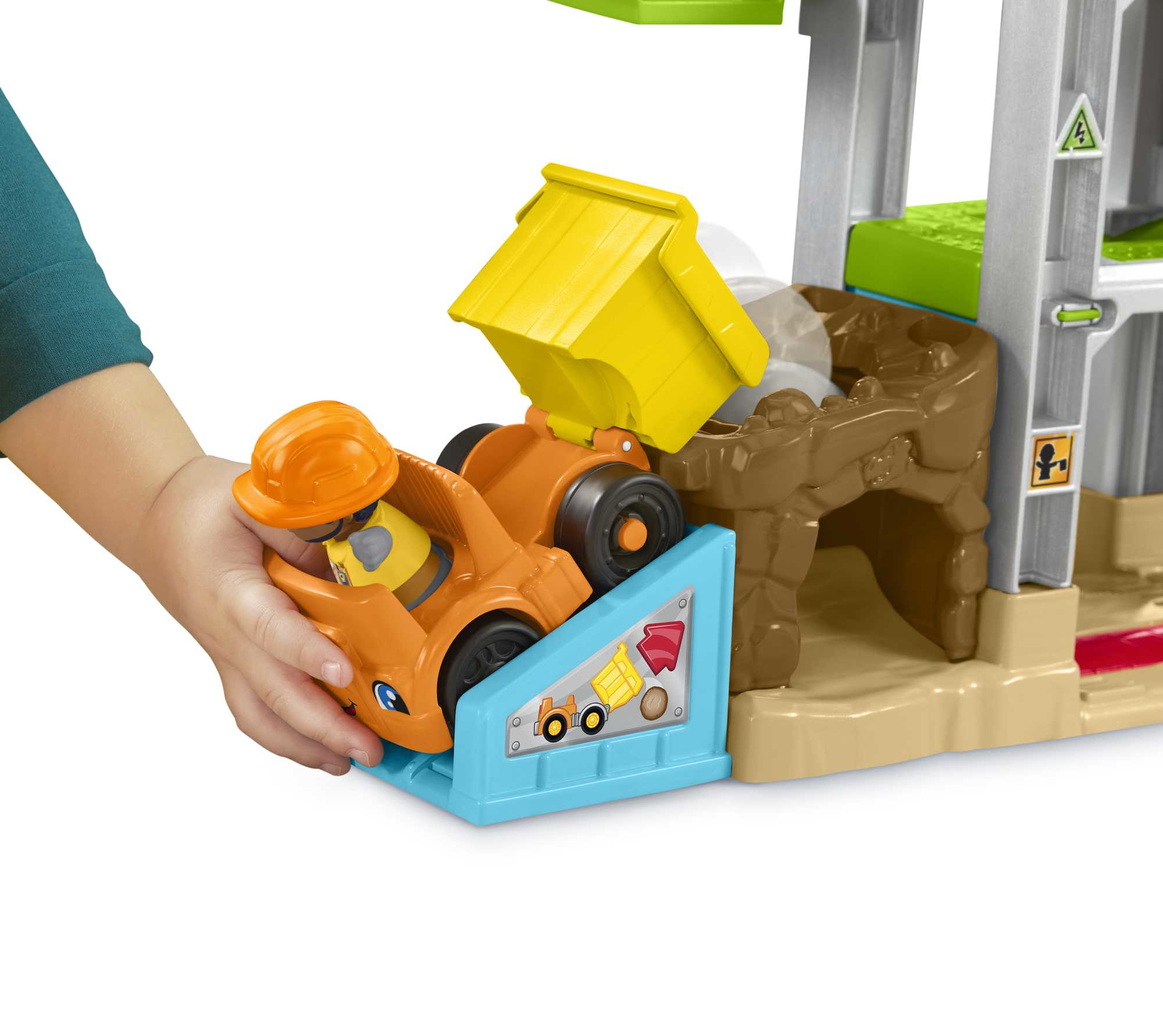 Un niño juega con un sitio de construcción de juguete, un camión amarillo que se vuelca en un agujero marrón.