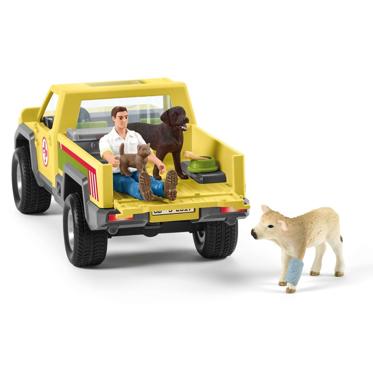 Ein gelber Lastwagen mit einem Mann, einem Hund und einer Katze auf der Rückseite und einem Kalb mit Verband.
