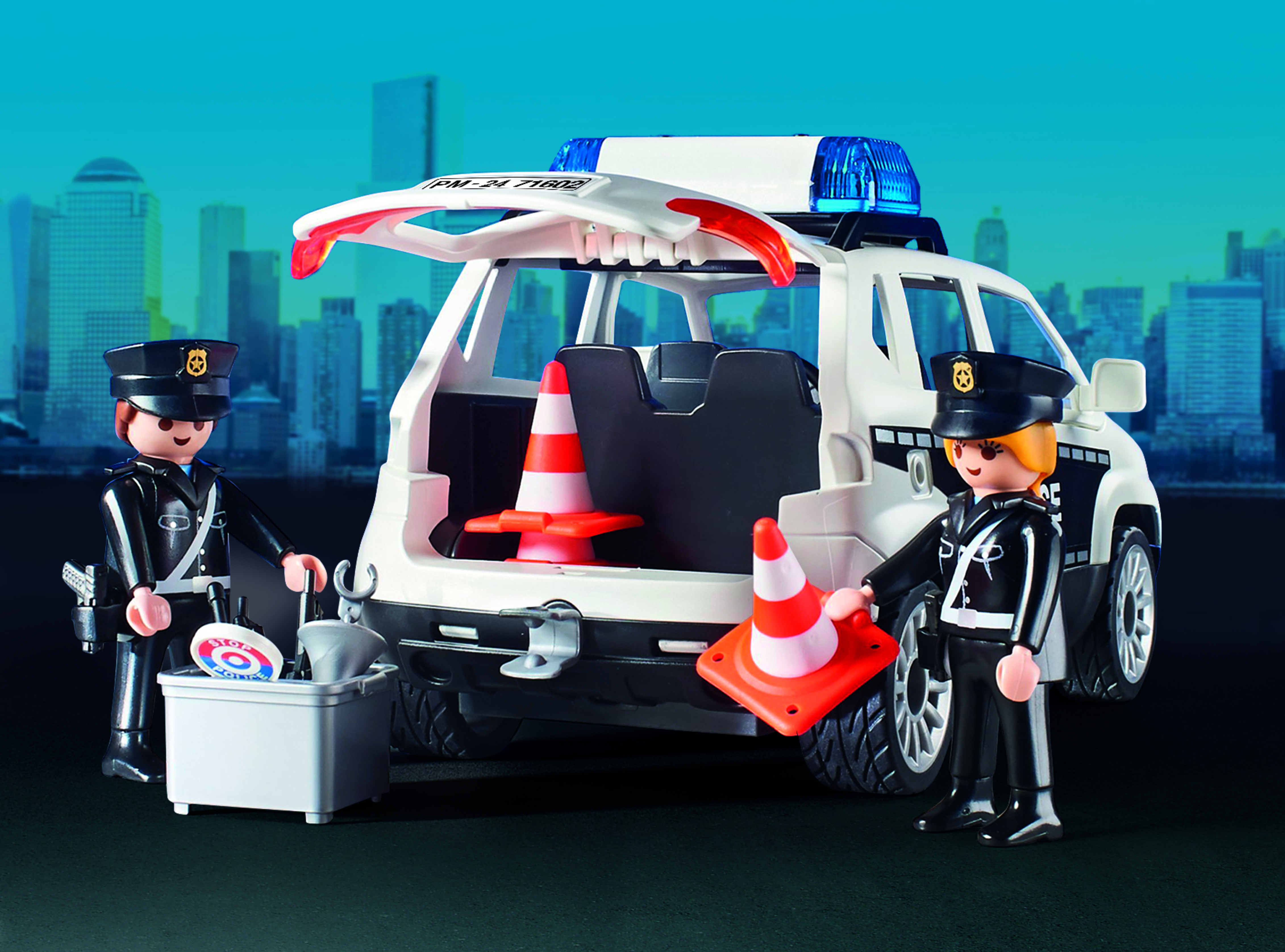Giocattolo dell'auto della polizia Playmobil con due agenti e coni stradali, contro uno skyline urbano.