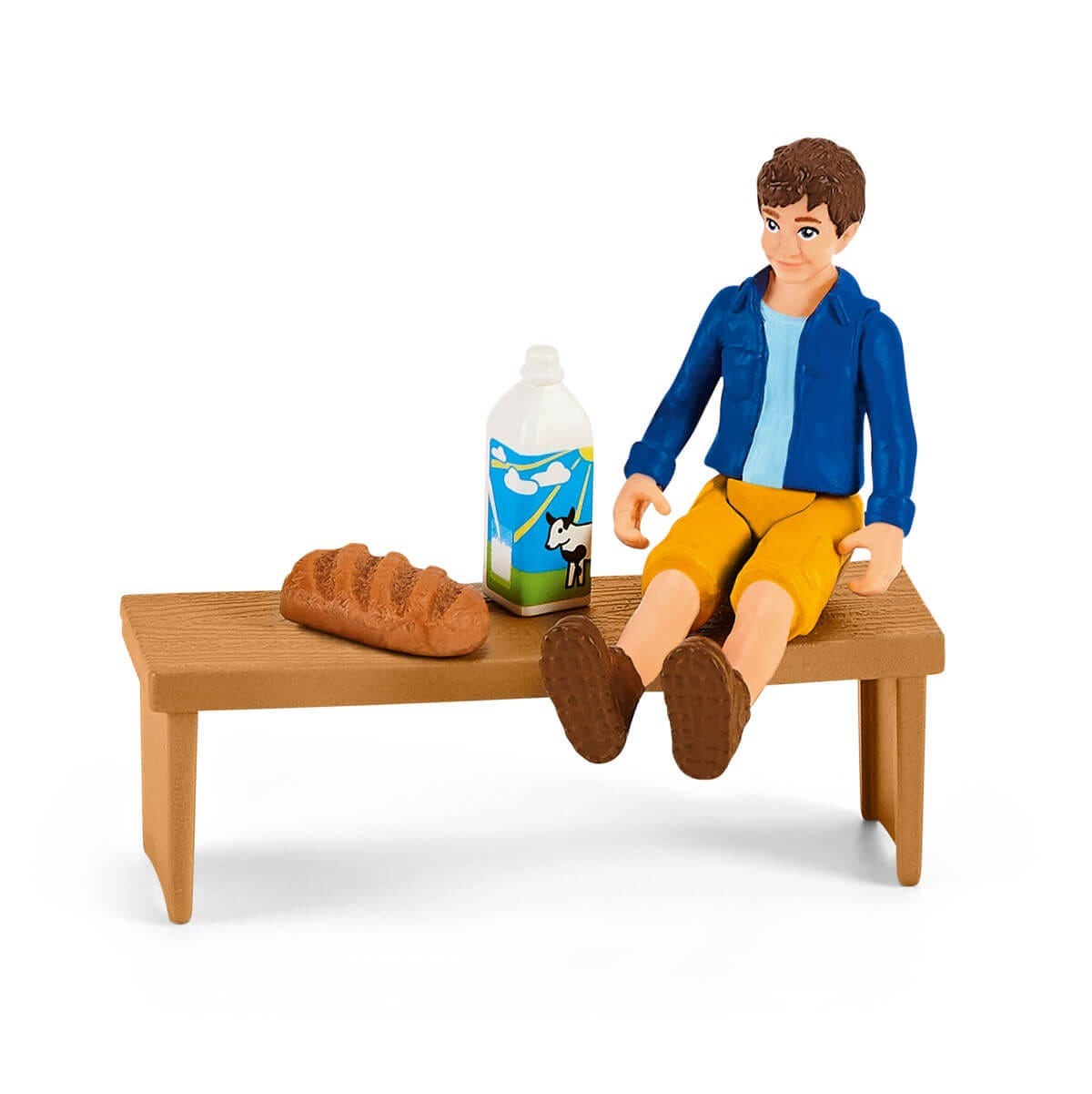 Figurka siedzi na ławce z chlebem i kartonem mleka.