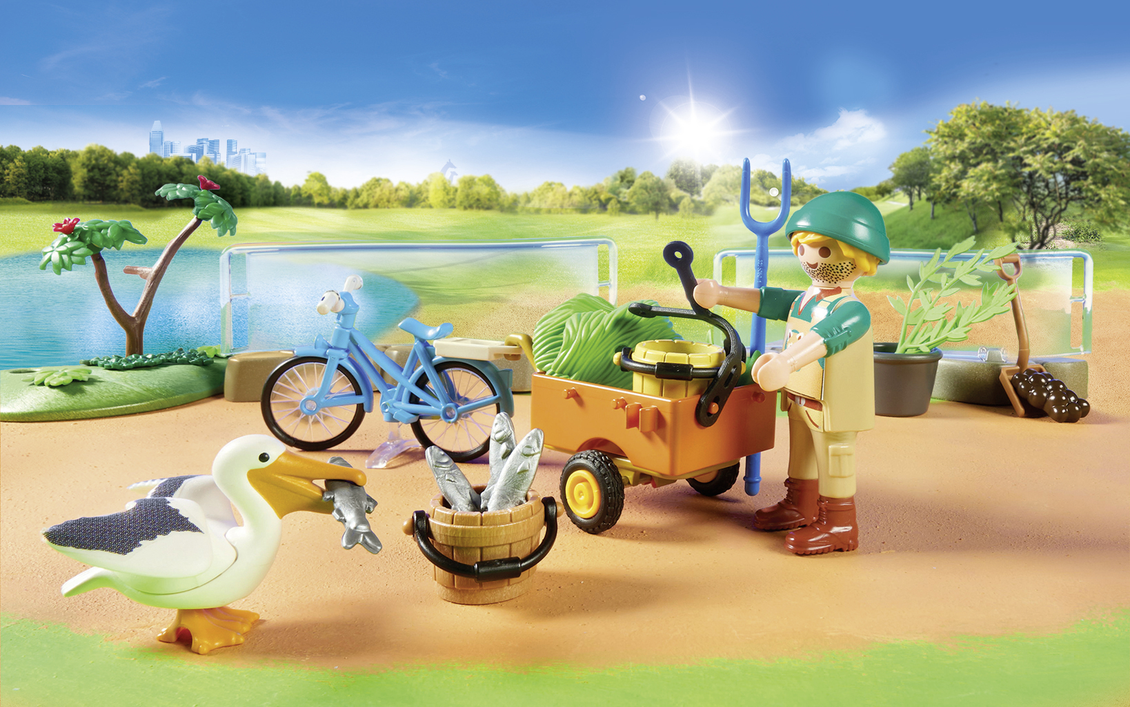 Eine Spielzeugszene eines Mannes mit einem Wagen, Fahrrad, Pelikan und Fisch. Grünes Feld und blauer Himmel mit Stadt im Hintergrund.