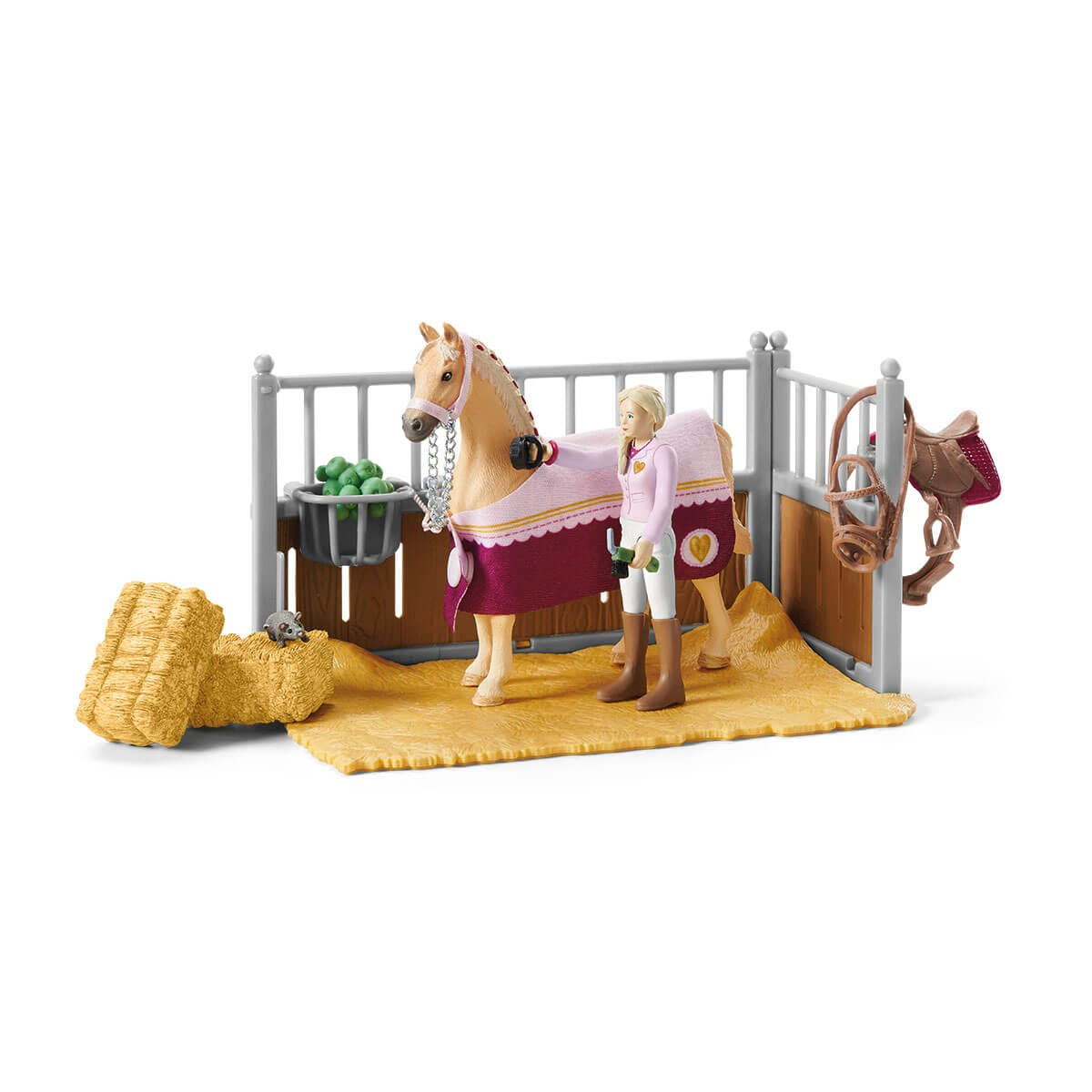 Ein Pferd und ein Mädchen in einem Stall. Das Pferd trägt eine Decke und hat Heu vor sich.