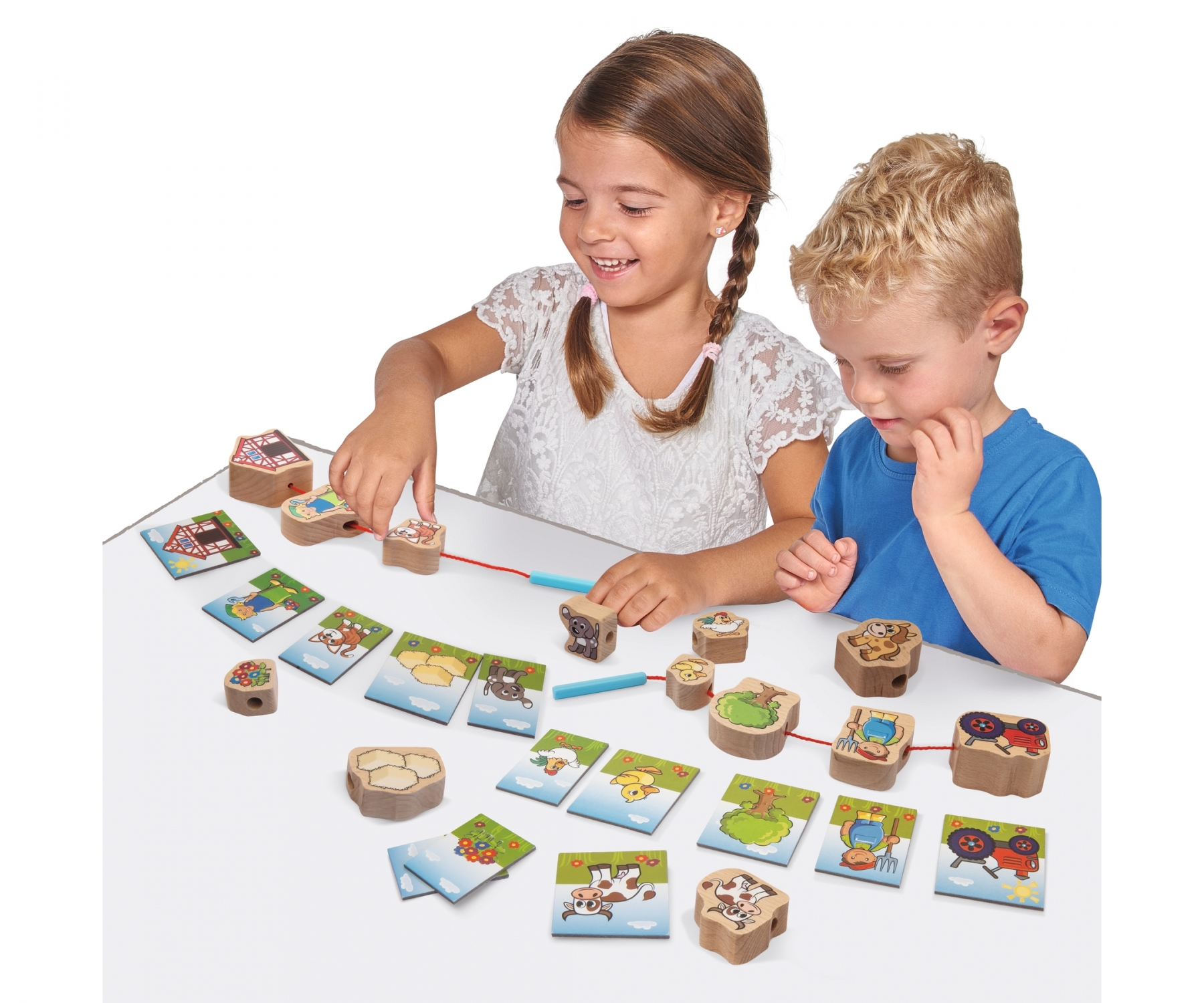 Zwei Kinder spielen ein Holzbauernhofspiel. Holzfliesen und Spielsteine auf weißer Oberfläche. Glückliche Gesichter.