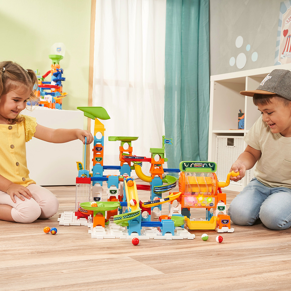 Zwei Kinder spielen drinnen mit einem bunten Konstruktionsspielzeug.