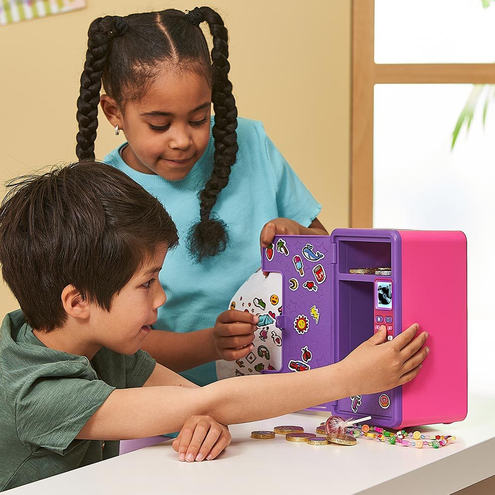 Zwei Kinder spielen mit einem rosa-lila Spielzeugtresor, Aufklebern und Süßigkeiten.