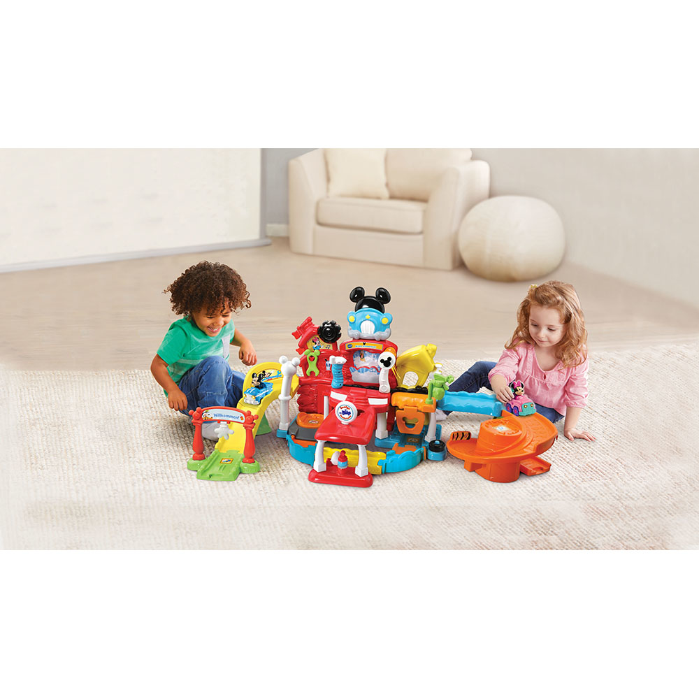 Zwei Kinder spielen mit einem Mickey Mouse Garage-Spielzeug mit mehreren Ebenen, Rampen und anderem Zubehör.