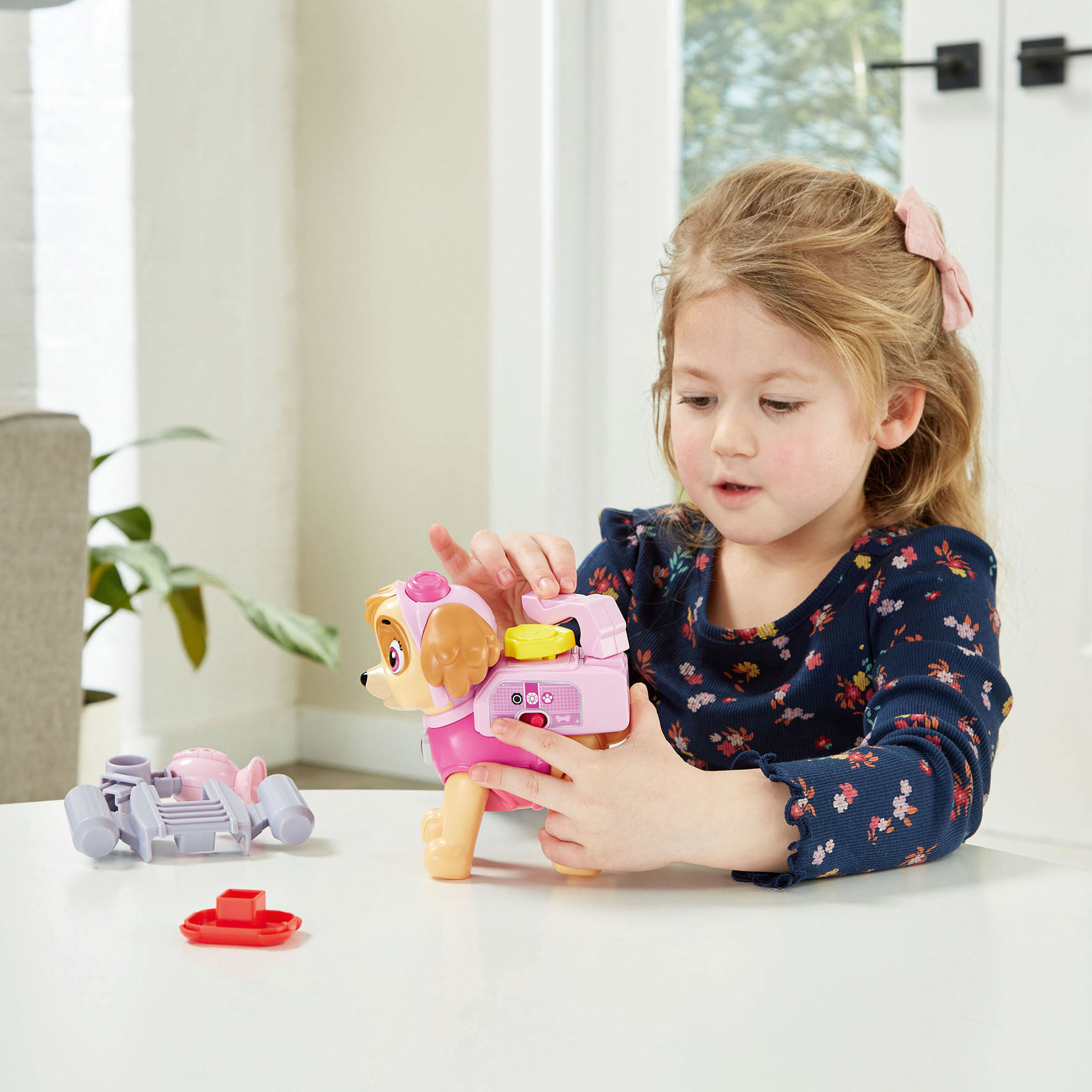 Ein Mädchen spielt mit einem pinken Spielzeughund, der ein Gadget ist.