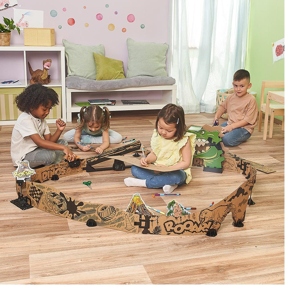 Vier Kinder spielen mit einem Dinosaurier-Spielset aus Pappe auf einem Holzboden.