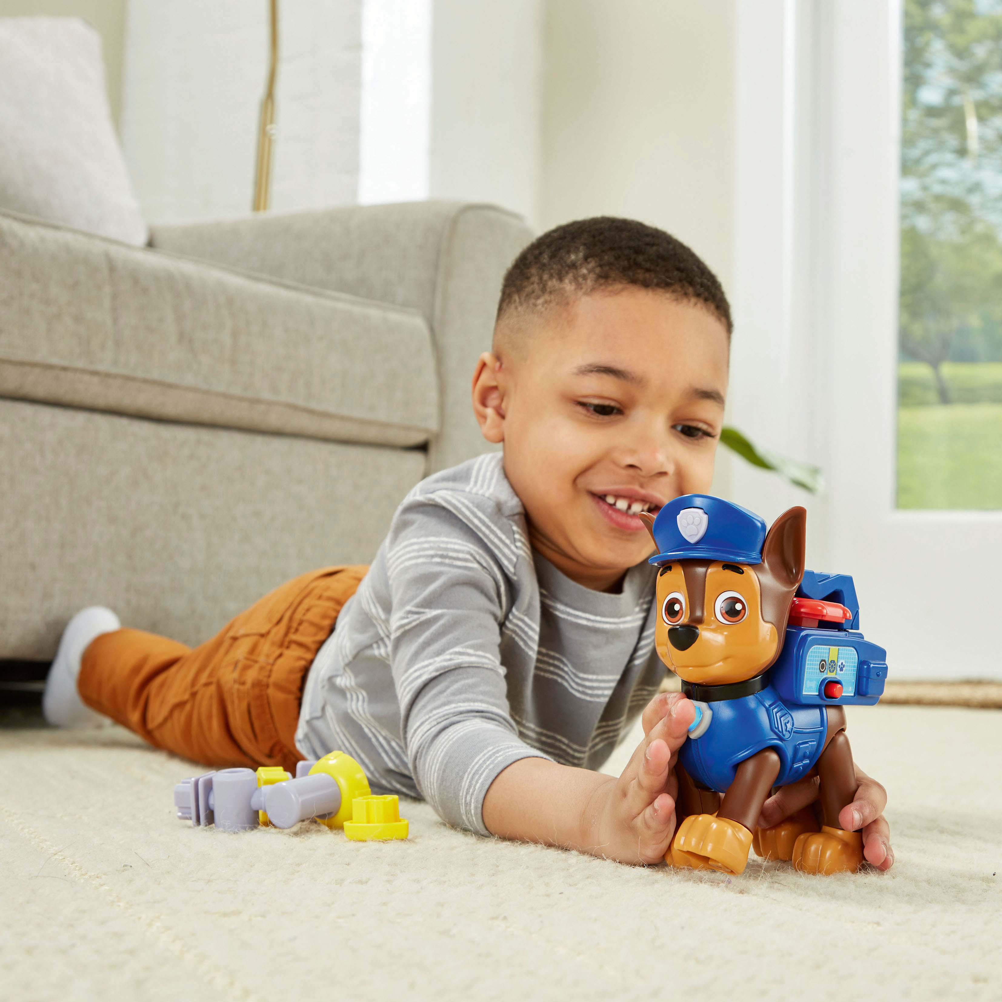 Un bambino gioca con un cane giocattolo, Chase di Paw Patrol. Il bambino sorride, il cane è blu.