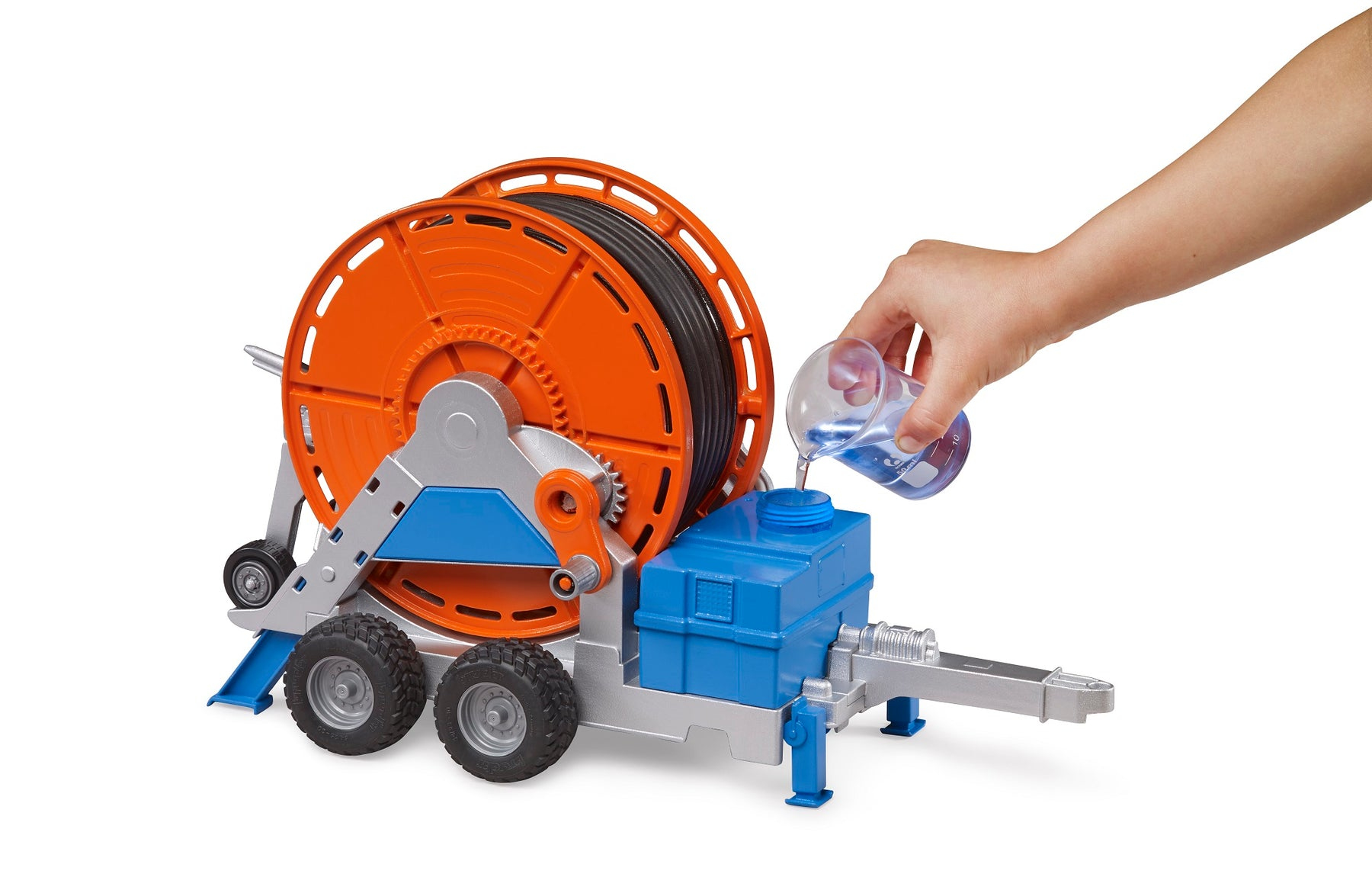 Eine Spielzeug-Wasserpumpe mit blauem Tank, roter Schlauchtrommel und einer Hand, die Wasser gießt.