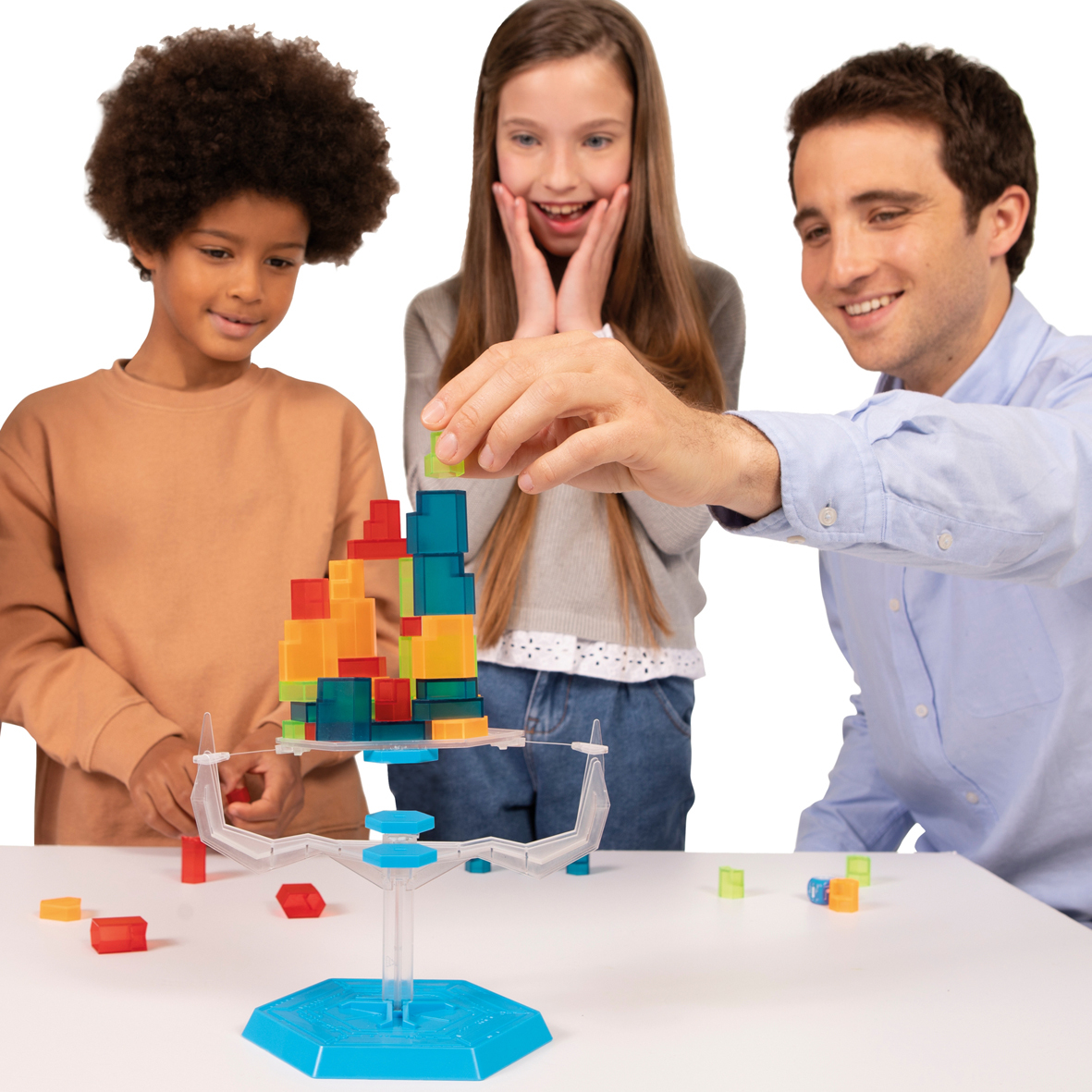Drei Personen spielen mit einem transparenten Spielzeug und balancieren bunte Blöcke.