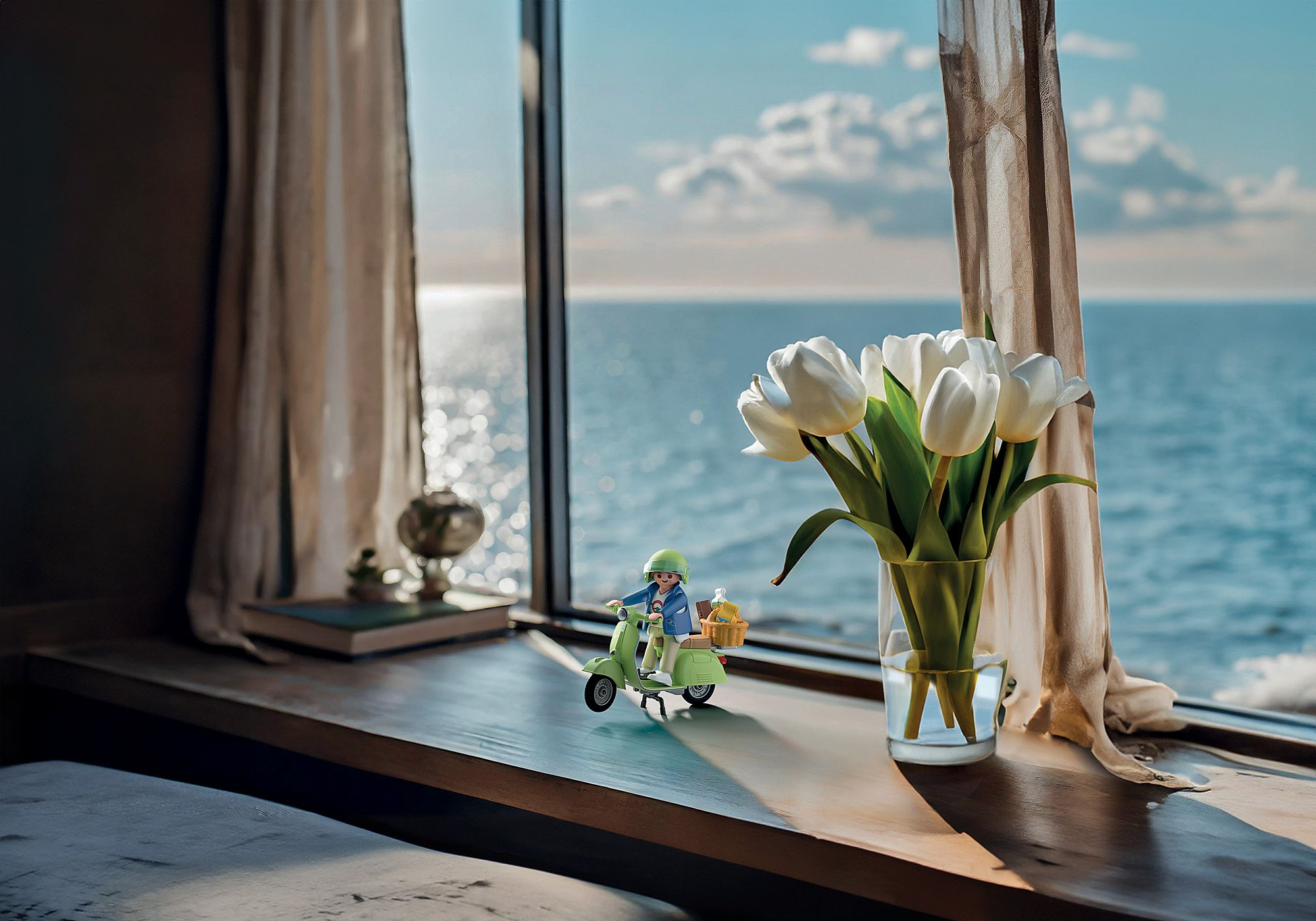 Zabawkowa figurka na skuterze z białymi tulipanami na parapecie z widokiem na morze.