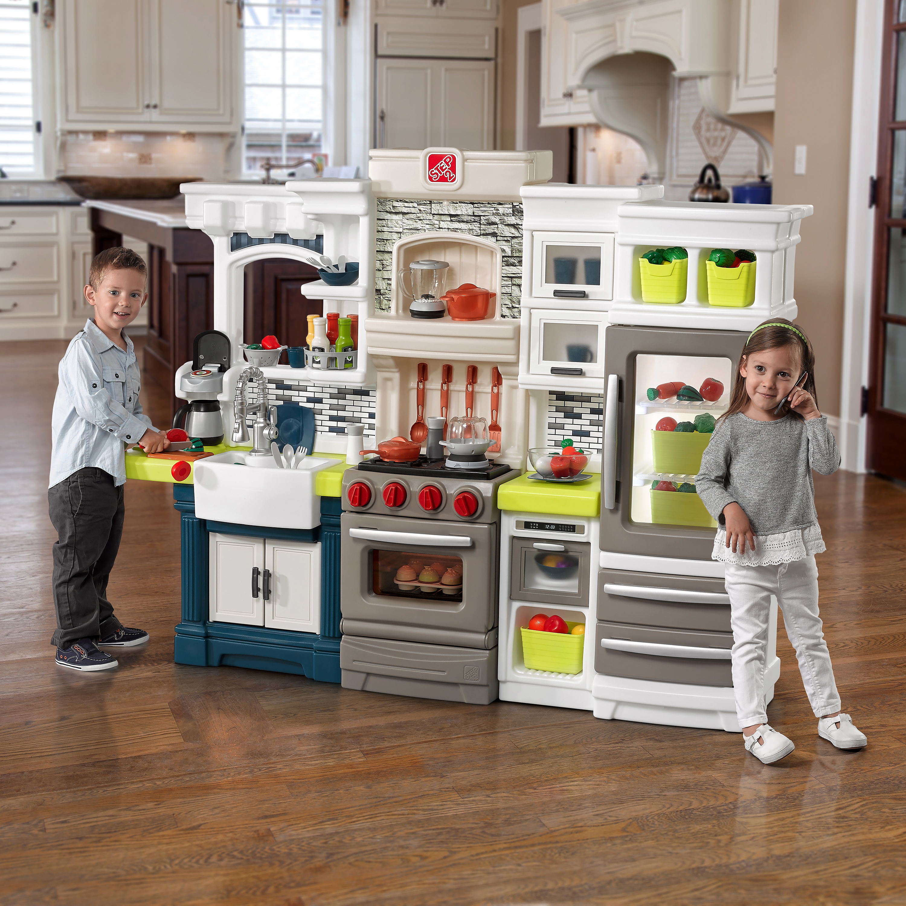 Kinder spielen mit einer Spielzeugküche. Küche hat Herd, Spüle, Kühlschrank und Zubehör.