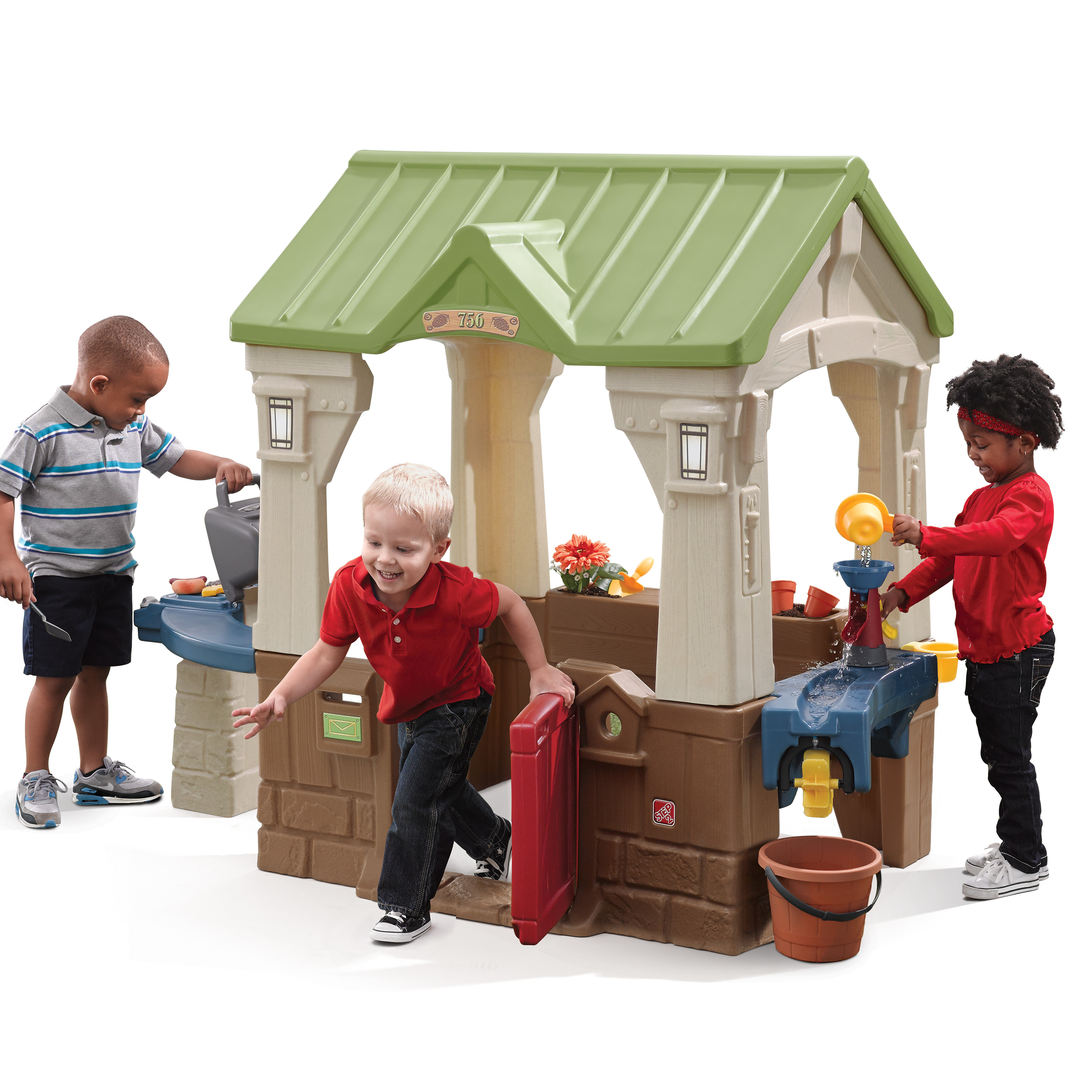 Drei Kinder spielen mit einem Spielhaus. Eines grillt, eines geht durch die Tür und eines benutzt eine Wasserfunktion.