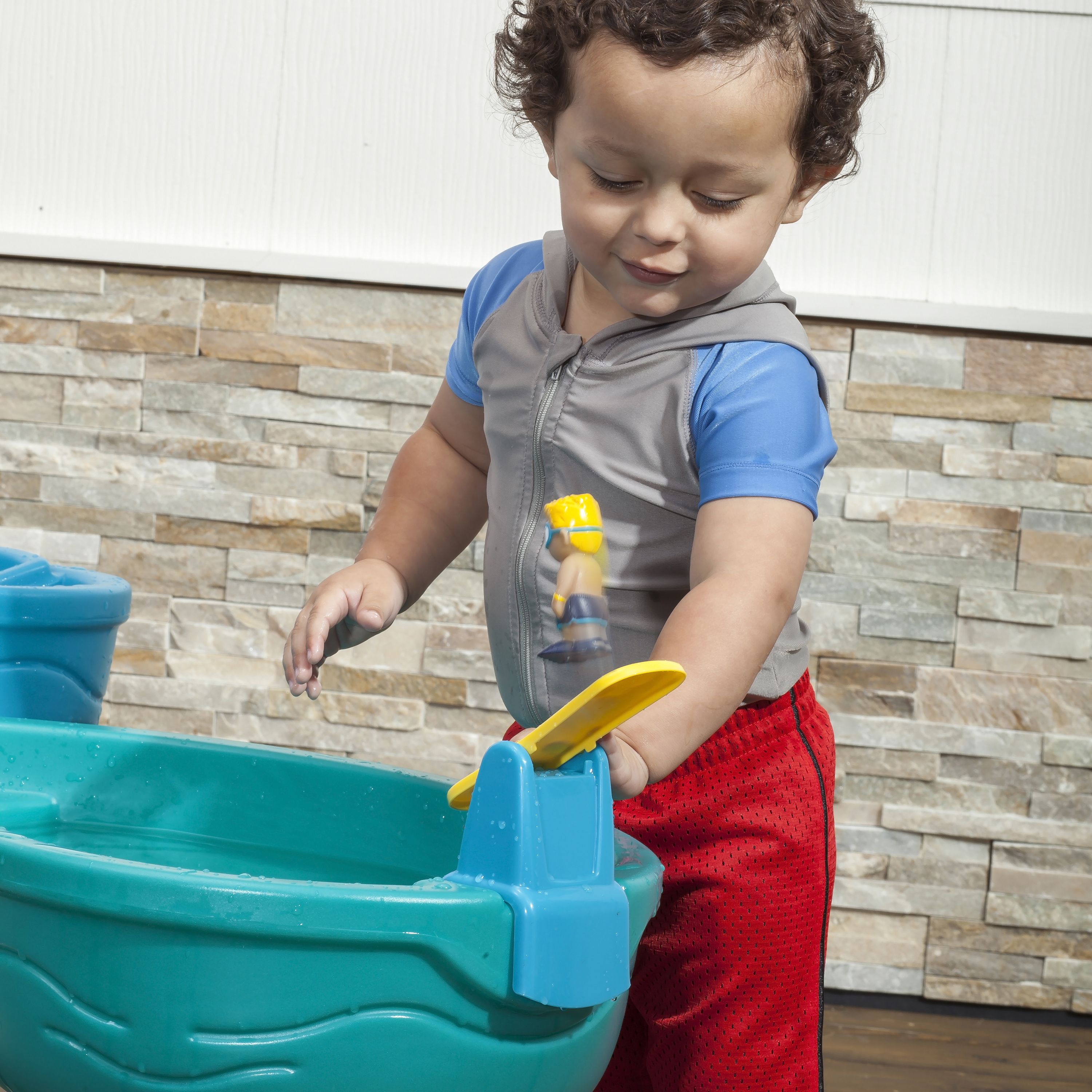Ein kleiner Junge spielt mit einem Wassertischspielzeug mit einer kleinen Figur.