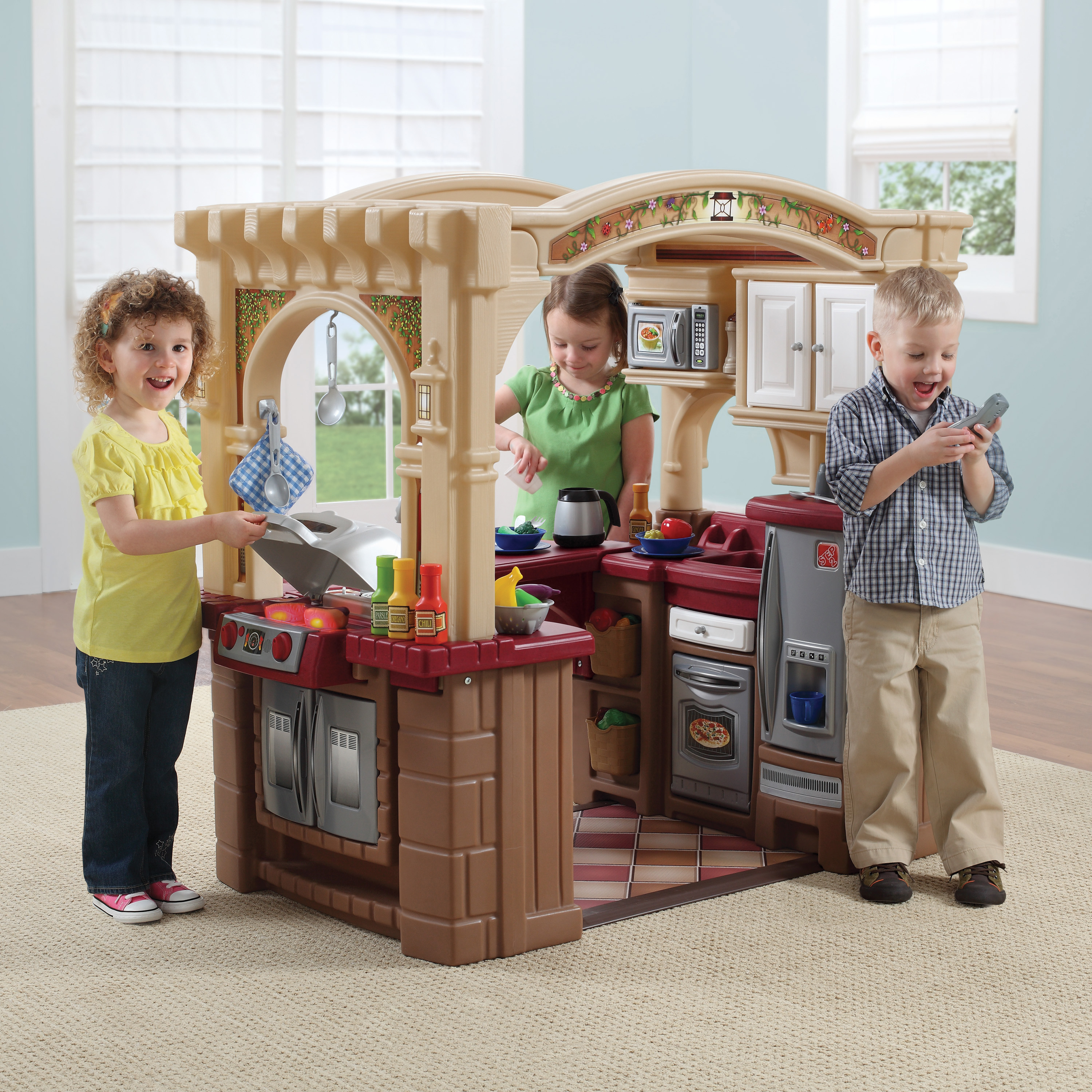 Drei Kinder spielen mit einer Spielzeugküche, Inneneinstellung.