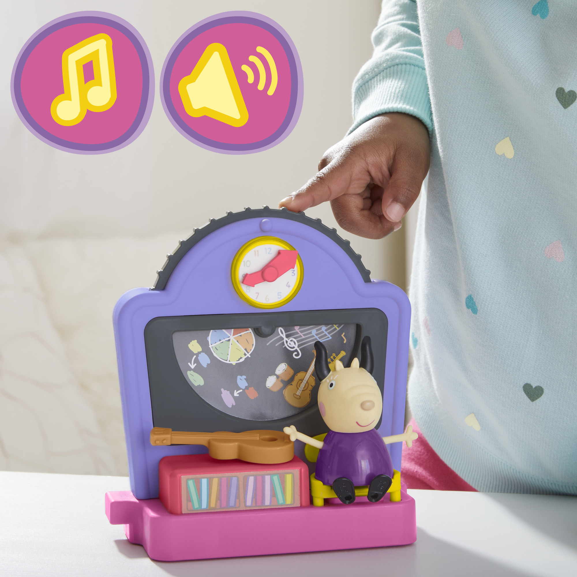 Die Hand eines Kindes zeigt auf einen Spielzeug-Musikplayer mit einer Peppa Wutz Figur.