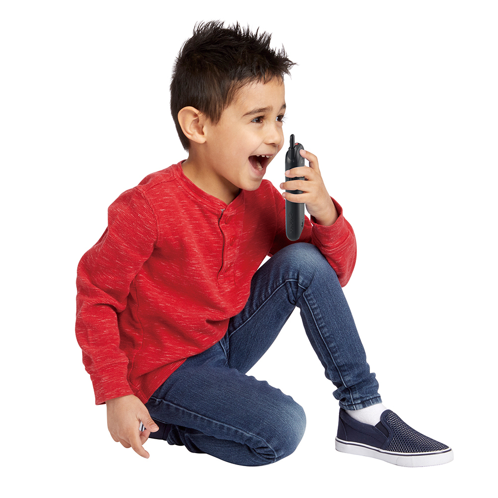 Ein junger Junge sitzt und hält ein schwarzes Spielzeug-Walkie-Talkie, wobei er mit offenem Mund schreit.