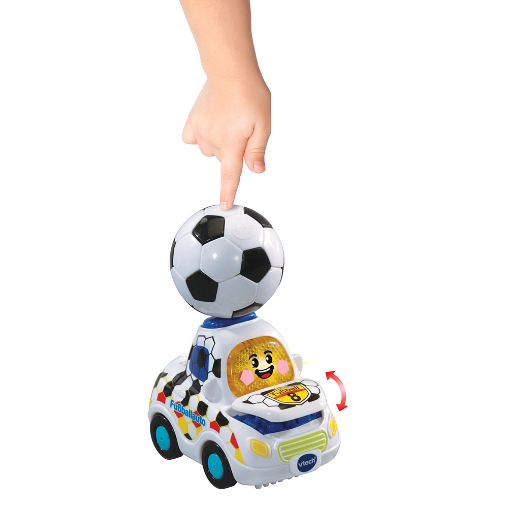 Der Finger eines Kindes zeigt auf einen Fußball auf einem weißen Autosspielzeug mit Lichtern.