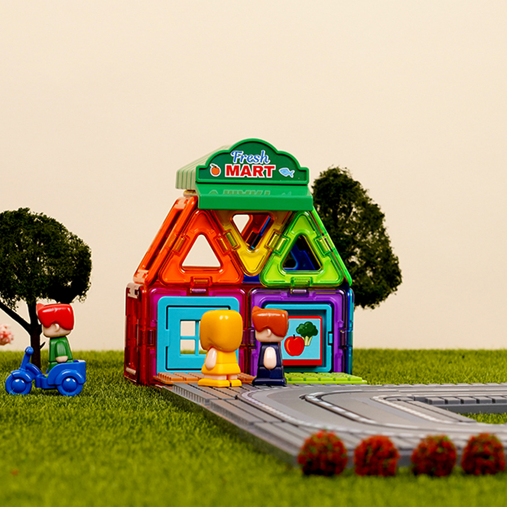 Spielzeughaus aus bunten Blöcken mit Spielfiguren und einer Straße. Grünes Gras im Hintergrund.