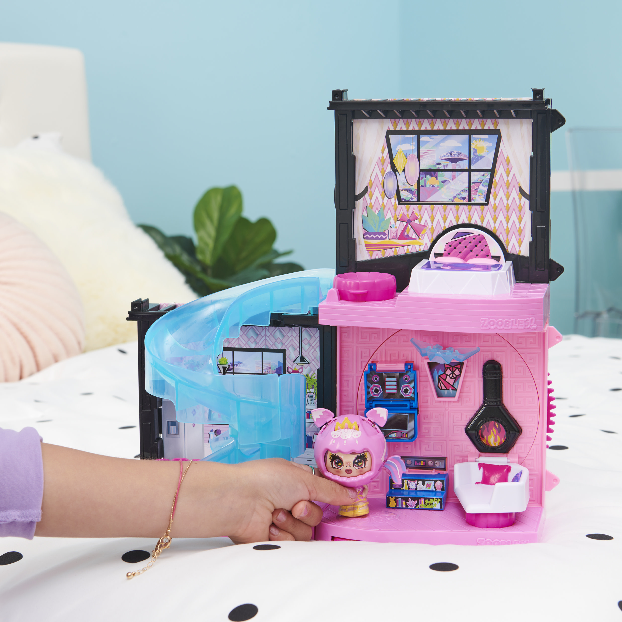 Ein rosa Spielzeughaus mit einer Puppe. Das Haus hat eine Rutsche und mehrere Zimmer.